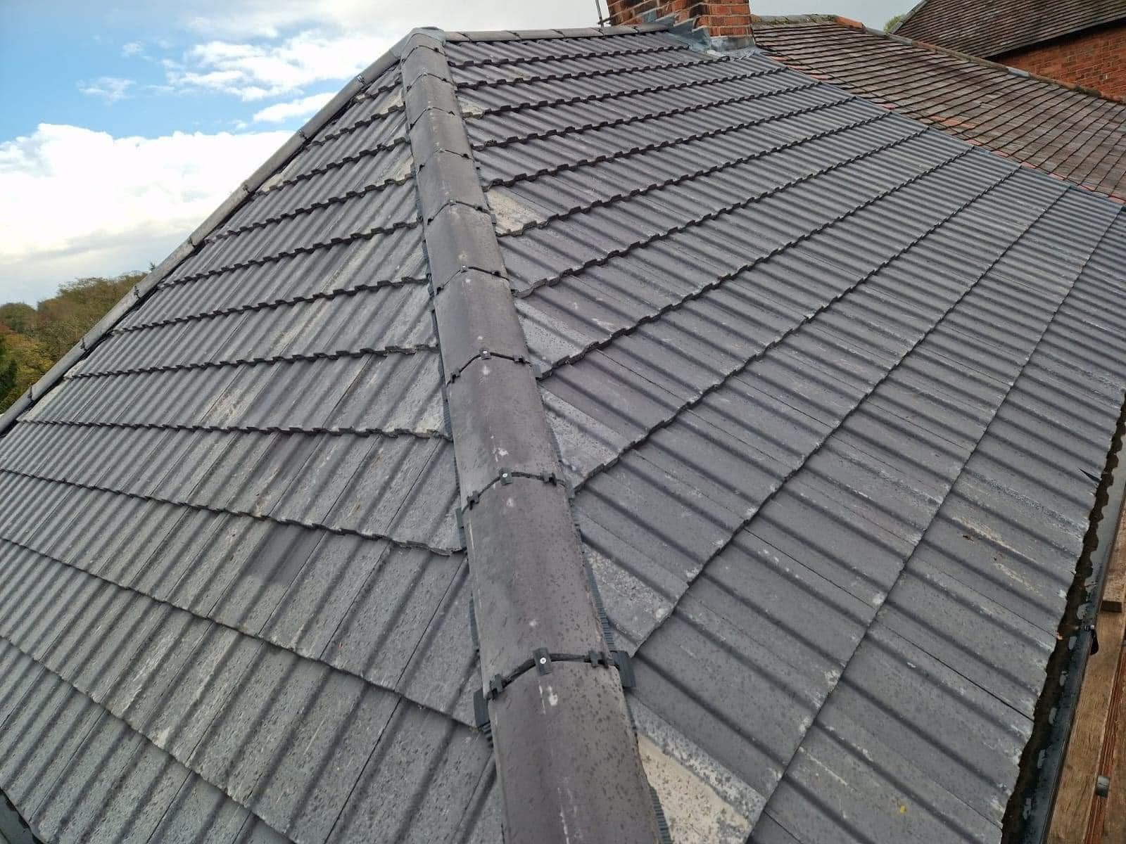Gray tiled roof with a central ridge and sky visible in the background