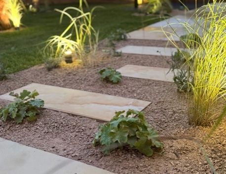 Illuminated gravel garden path with stepping stones and small plants at dusk