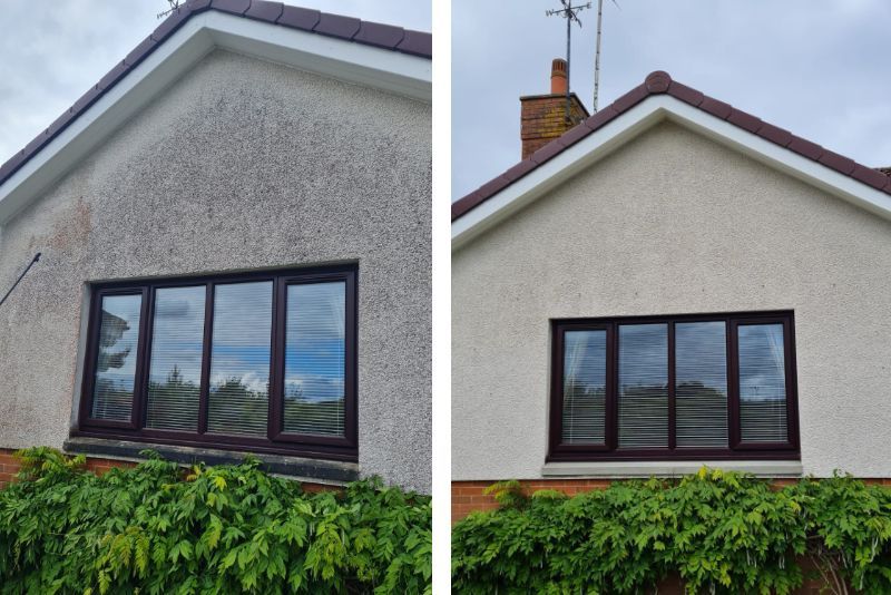 House exterior with white stucco walls, dark-framed window, and green hedge in front.