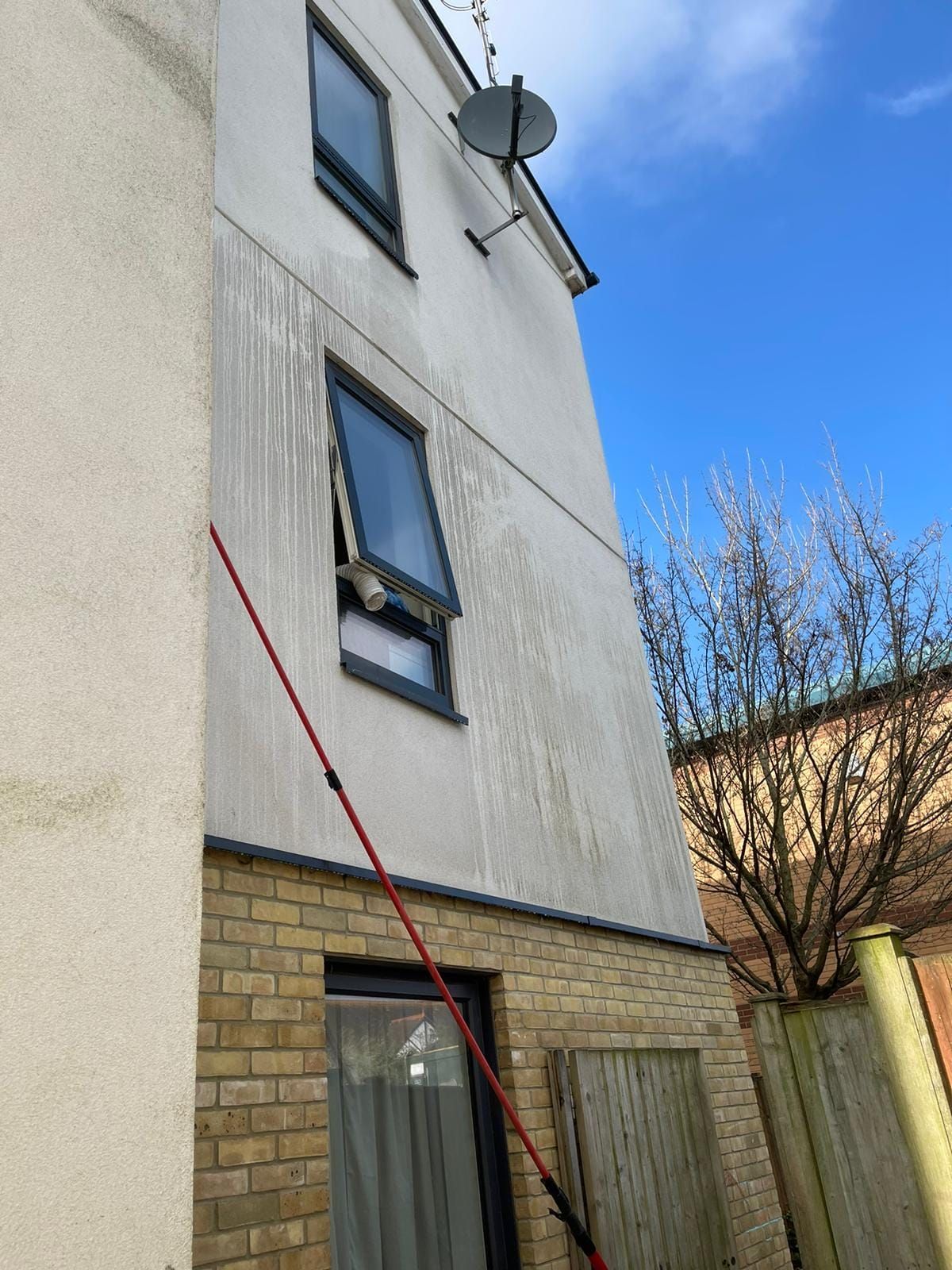 Exterior of a house with a satellite dish, two windows, and a red diagonal line drawn over the wall
