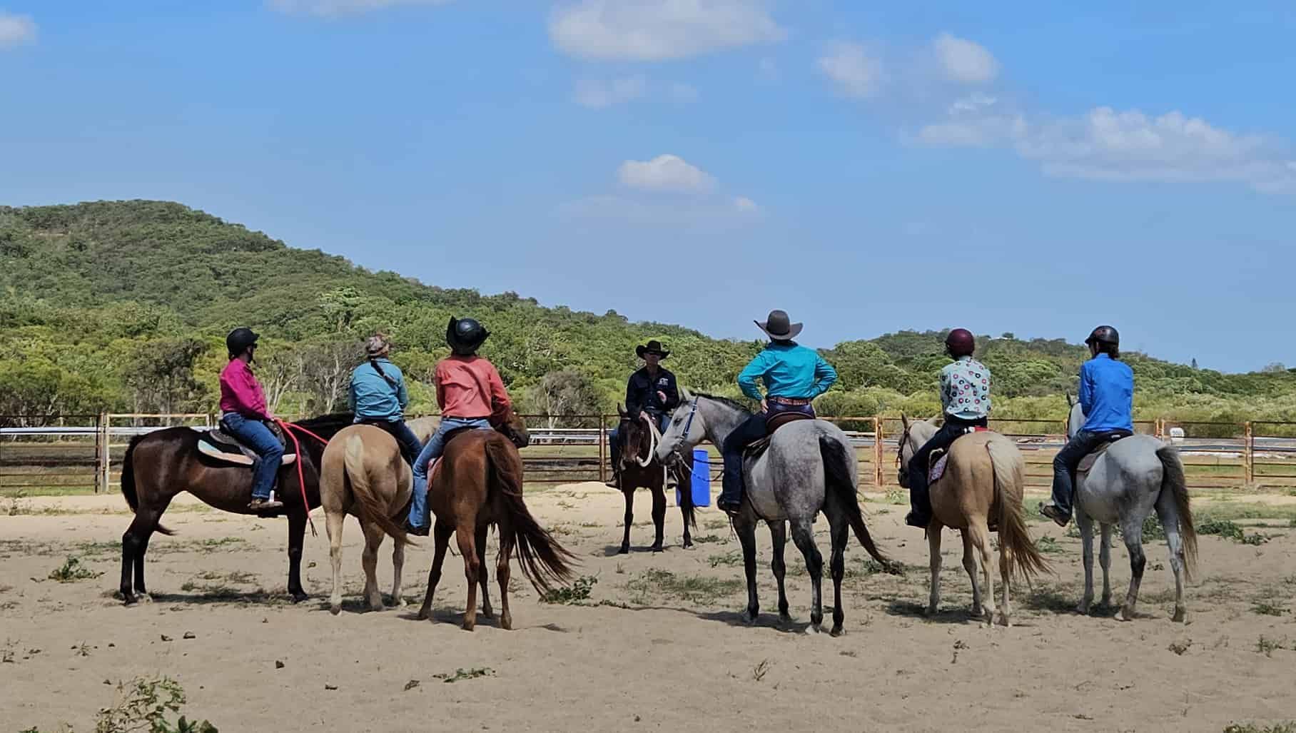 A Group Of People Are Riding Horses In A Field — Jono Battle Equine Services In Walkamin, QLD