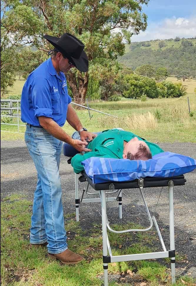 A Man In A Cowboy Hat Is Standing Next To A Man Laying On A Stretcher — Jono Battle Equine Services In Toowoomba, QLD