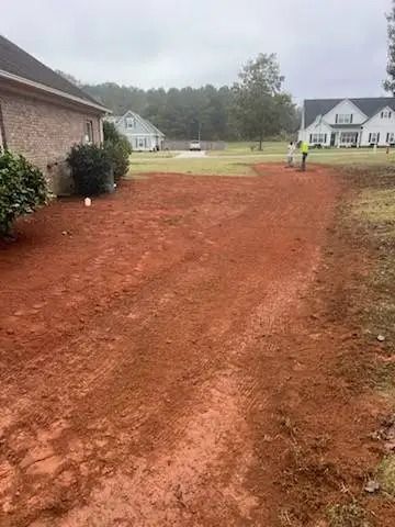 A dirt road leading to a house on a cloudy day.