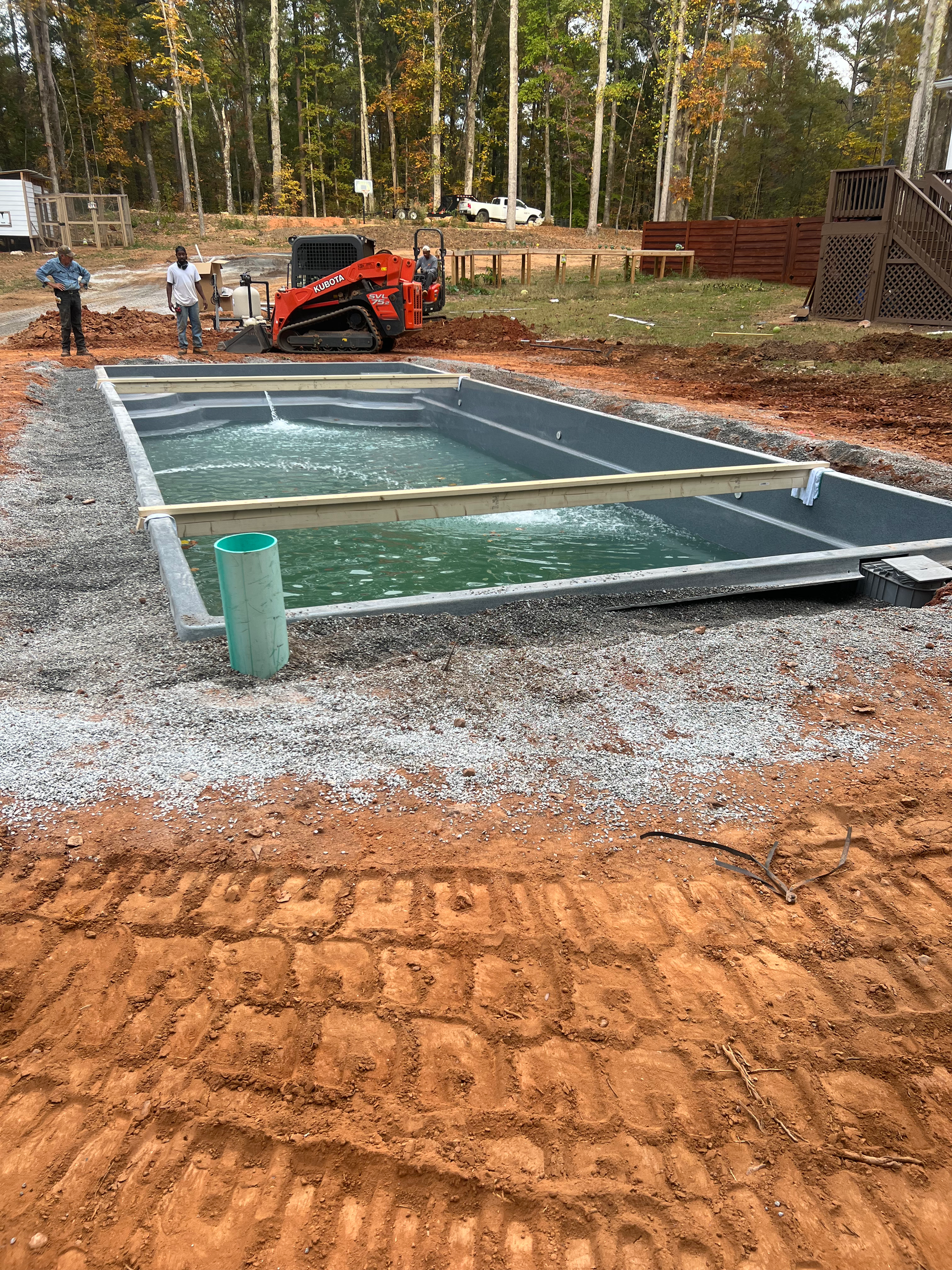 A large swimming pool is being built in a dirt field.