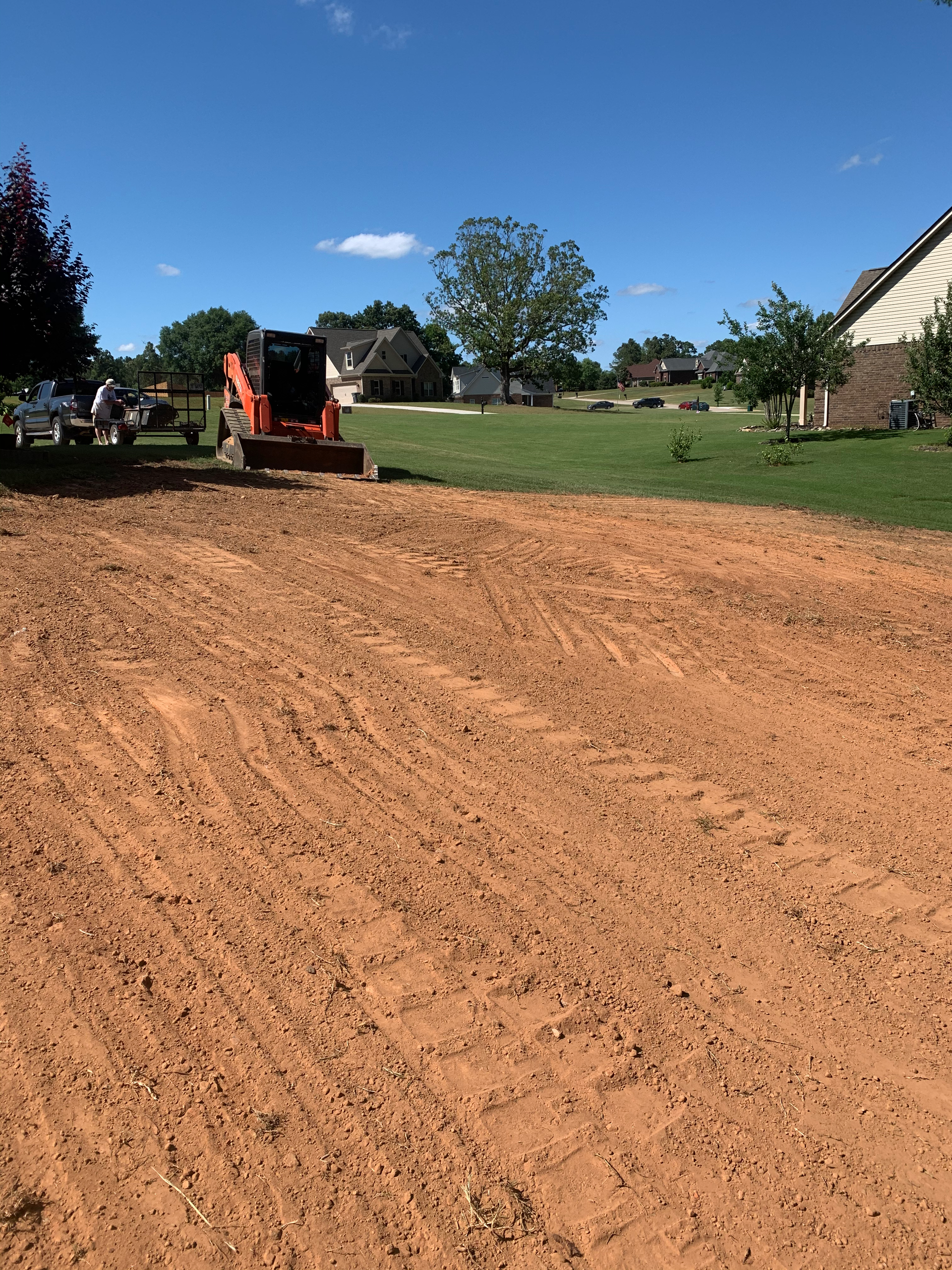 A bulldozer is moving dirt in a yard in front of a house.