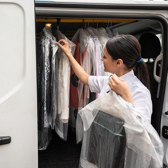 woman delivering dry cleaning out of van