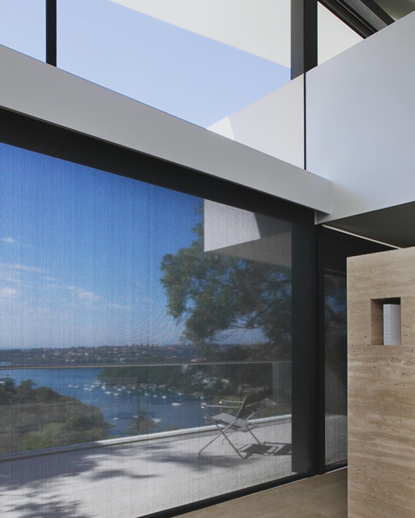 Large Window With a Mesh Shade Overlooking a Body of Water With Boats; Interior With White and Dark Trim