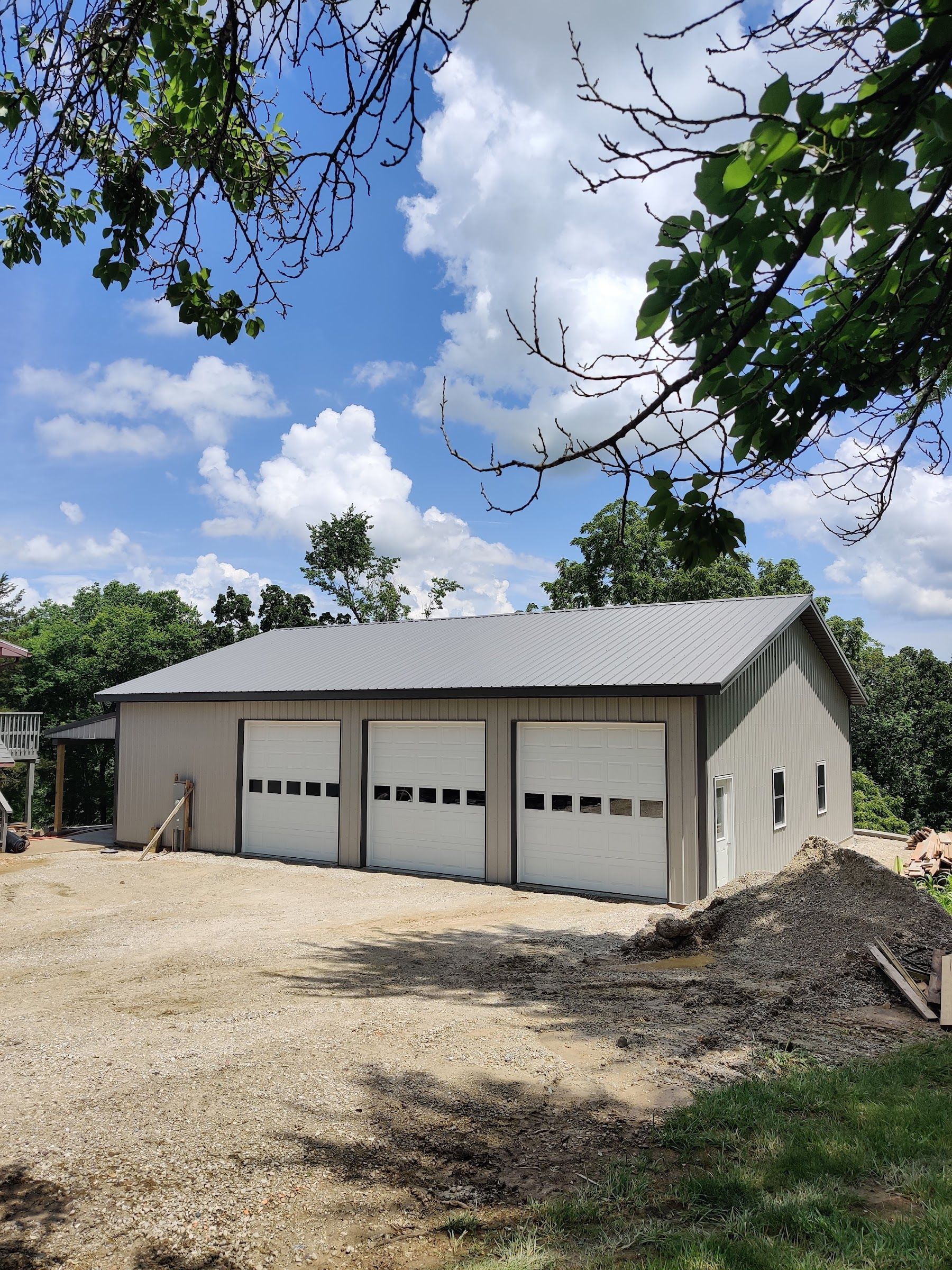 A garage with three white garage doors on a sunny day