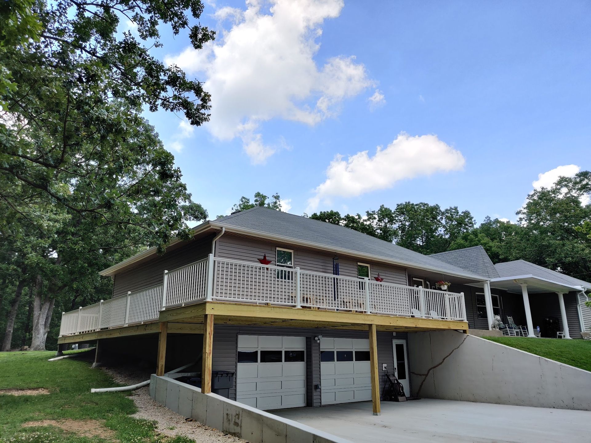 A large house with a large deck and a garage underneath it.