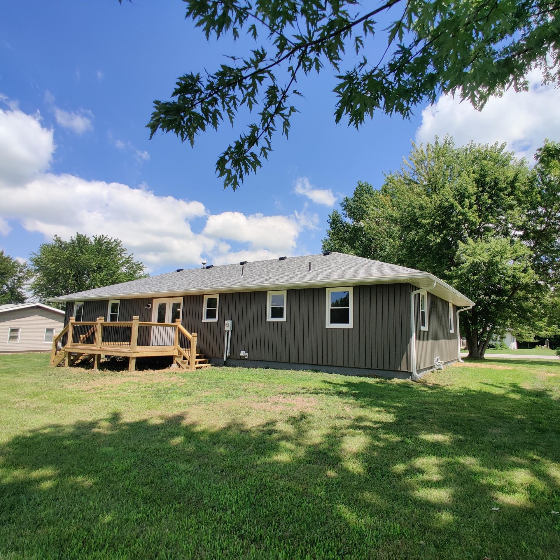 A house with a deck in the backyard on a sunny day
