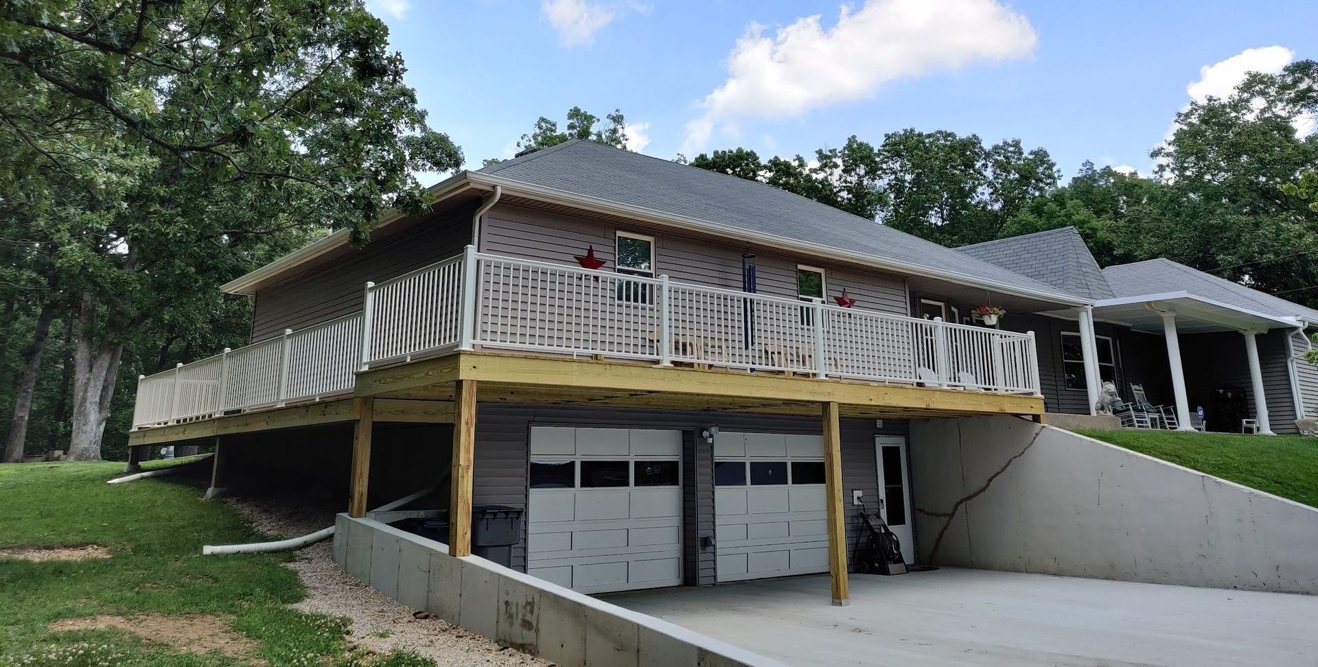 A large house with a large deck and two garages.