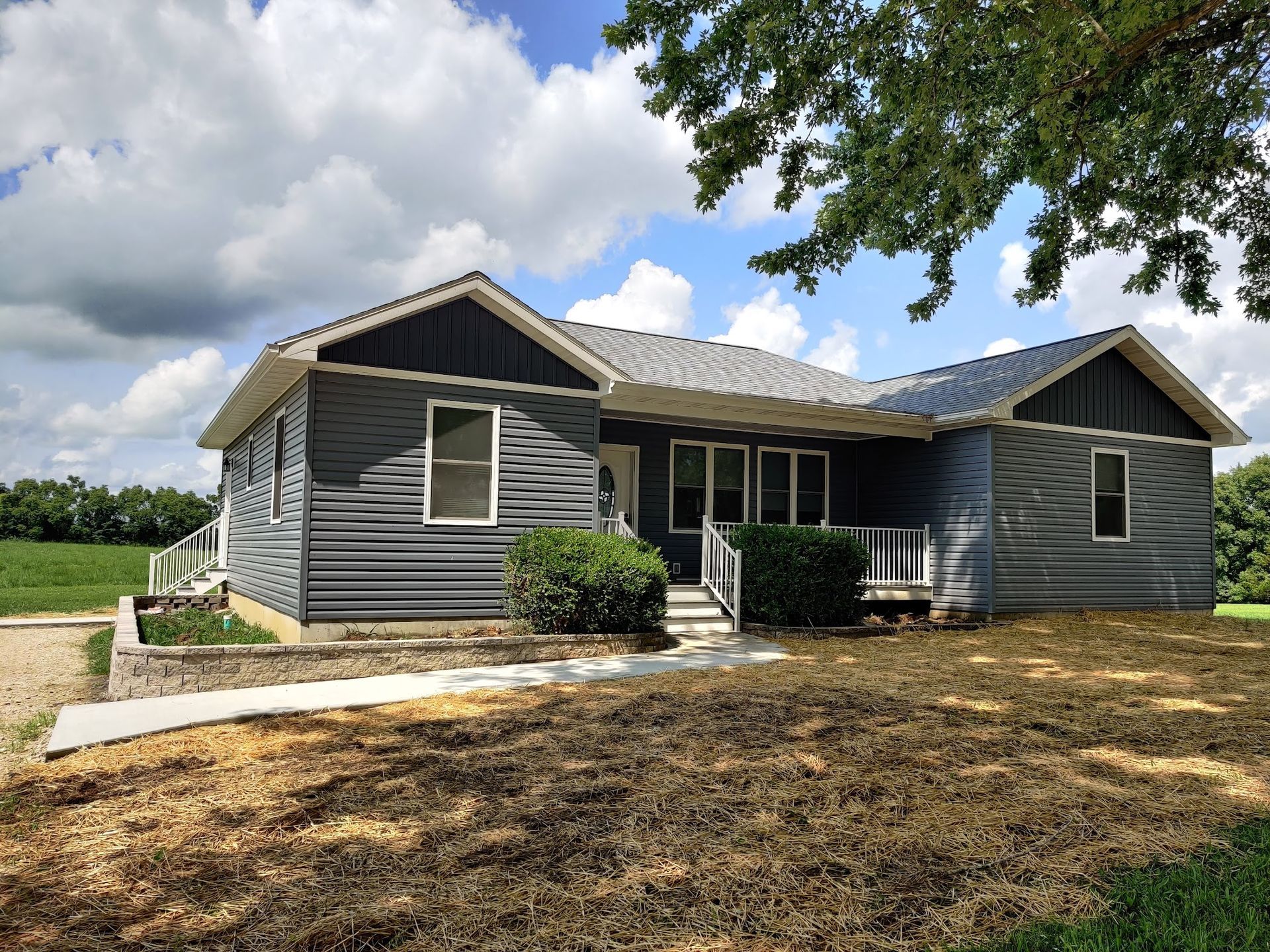 A house with a lot of windows is sitting in the middle of a field.