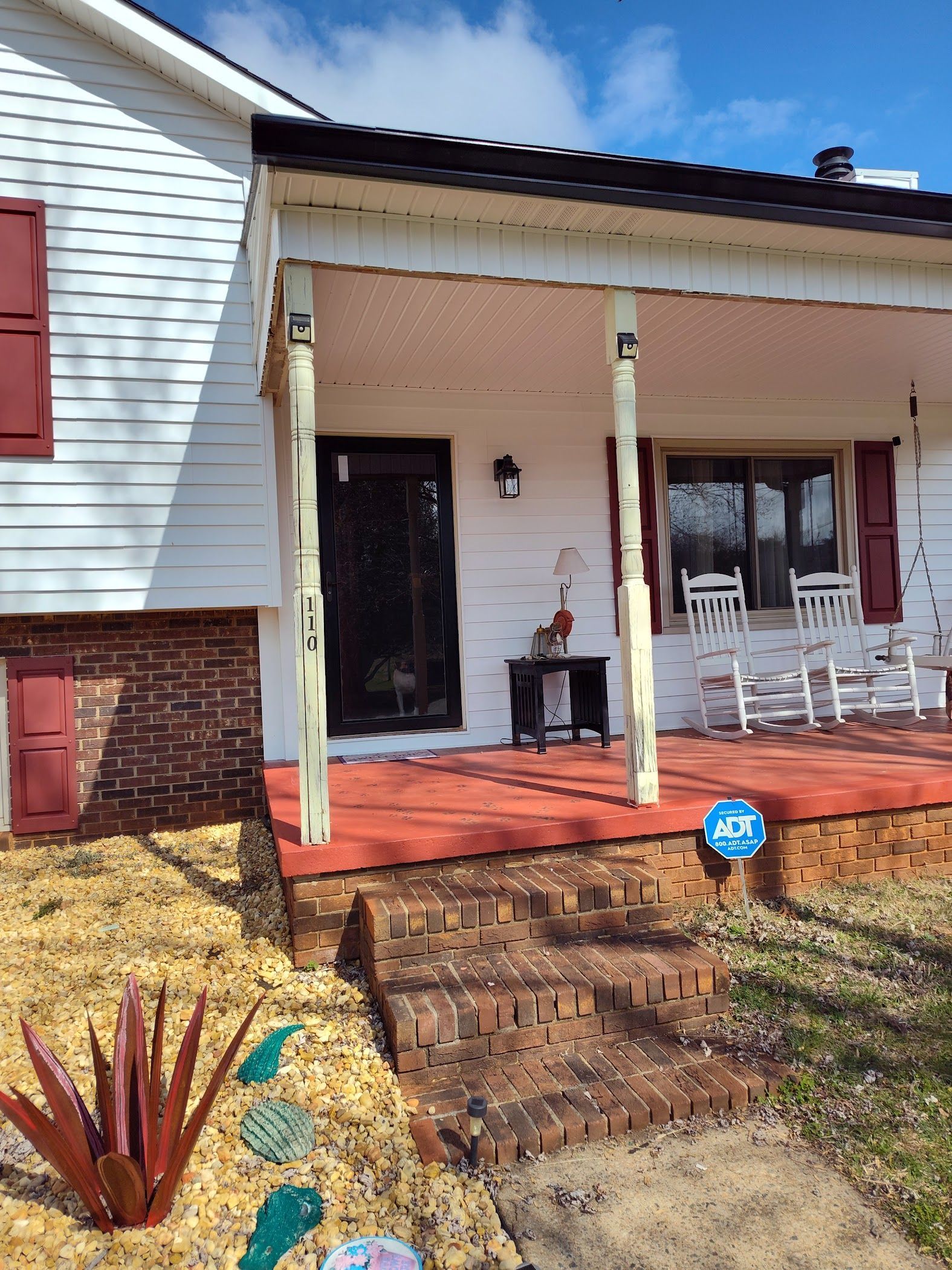 A white house with a porch and chairs on it.