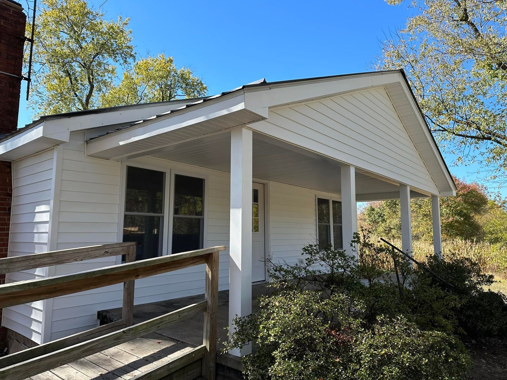 A small white house with a porch and a wooden ramp.