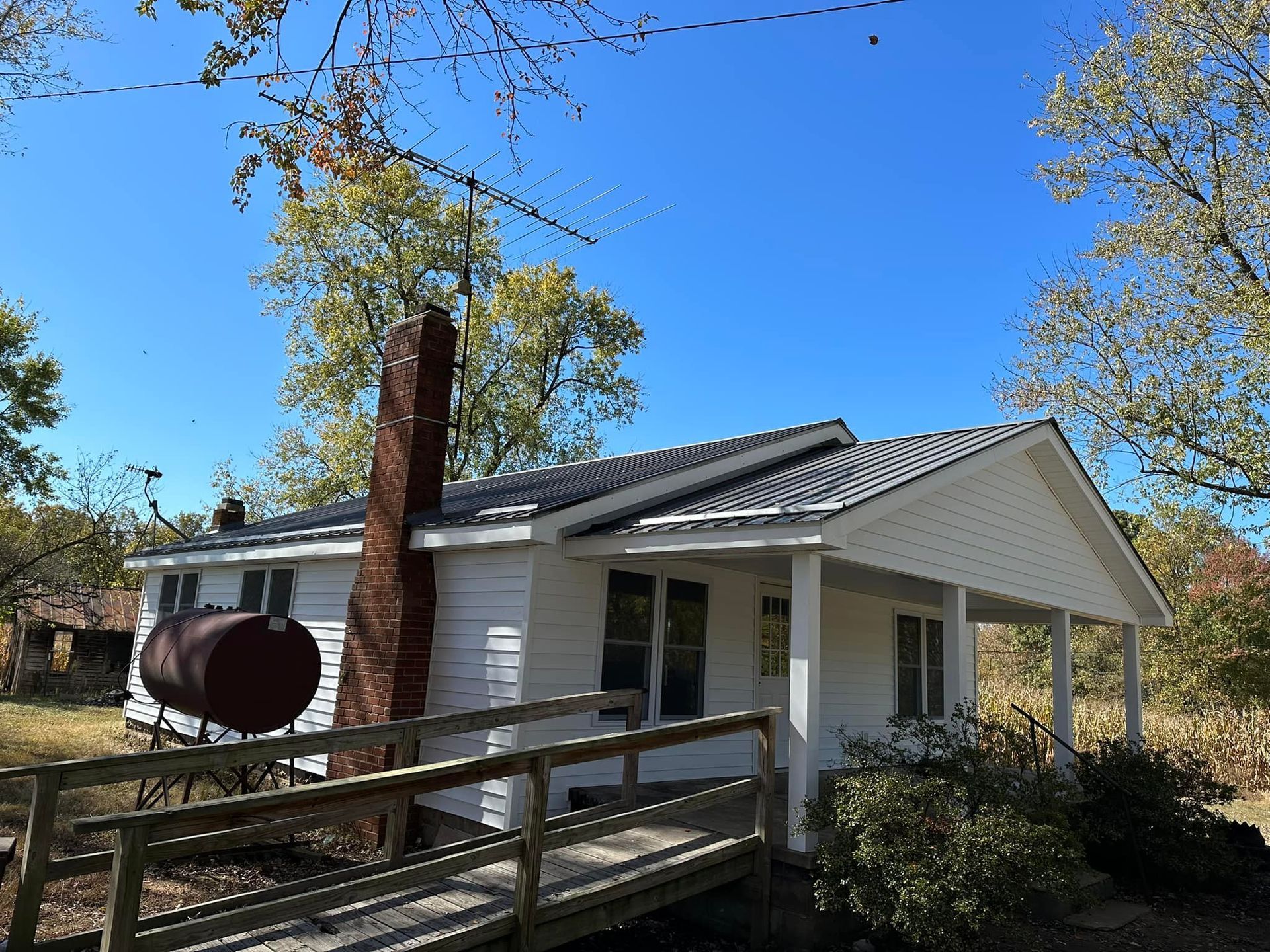 A small white house with a barrel on the porch