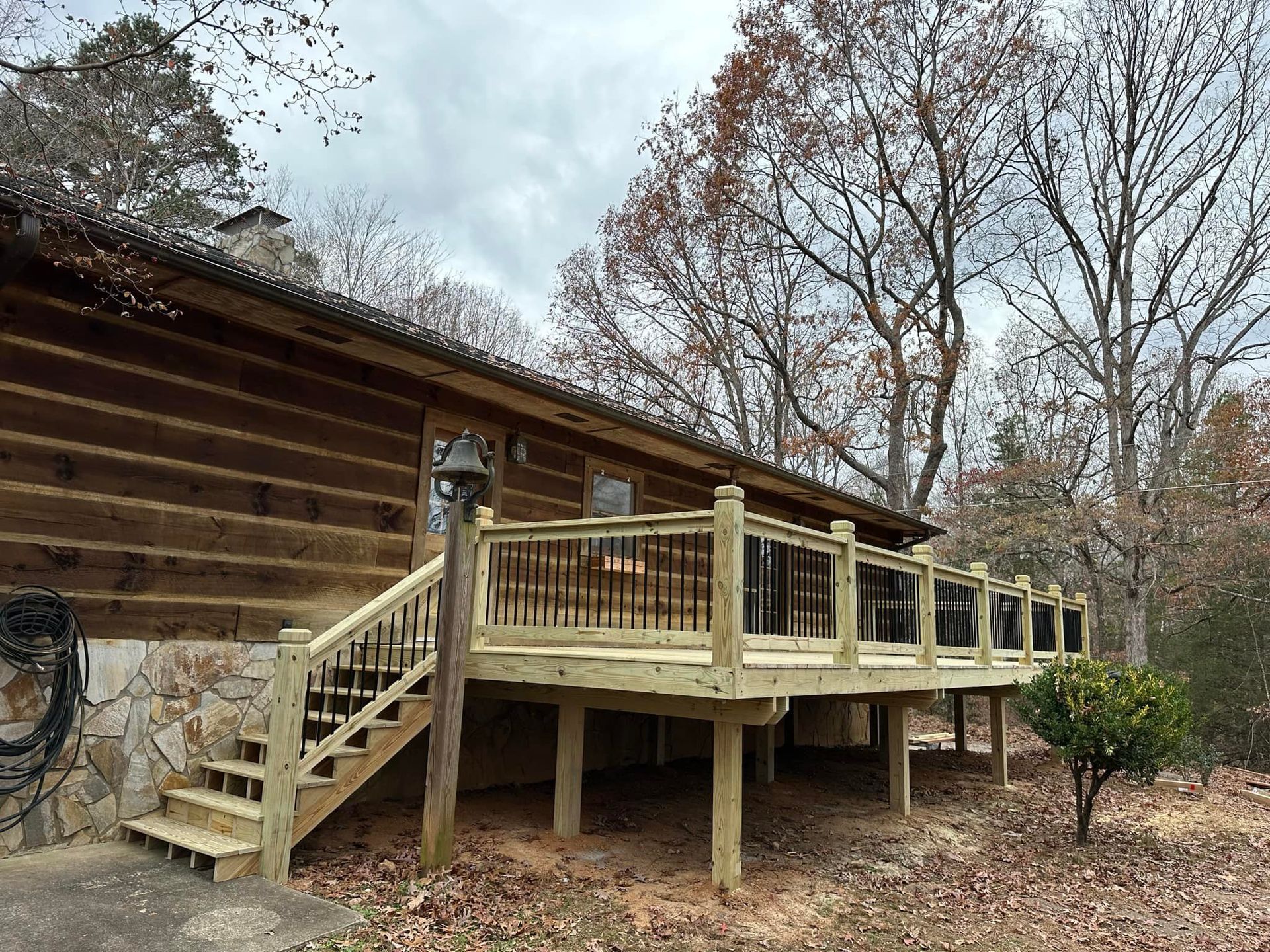 A wooden deck with stairs is in front of a log cabin.