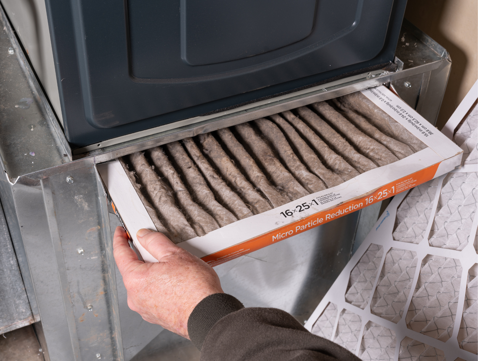 Person replacing a very dirty furnace filter.