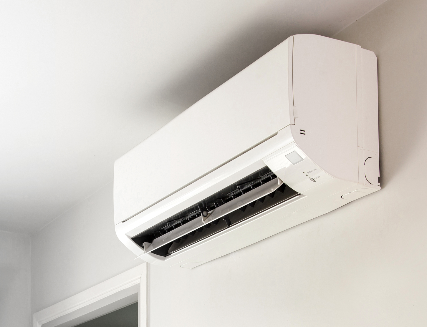 White wall-mounted air conditioner on a gray wall, indoors.