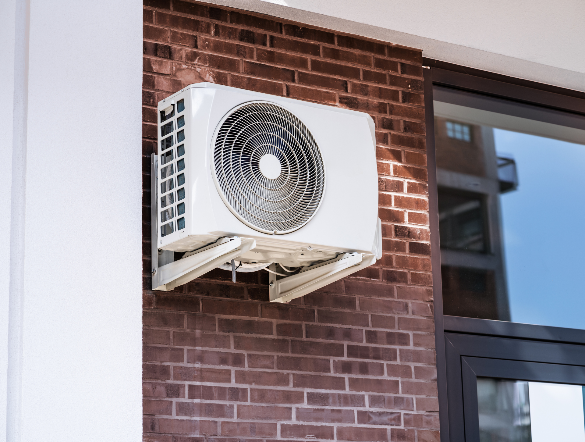 White air conditioning unit mounted on a red brick wall.