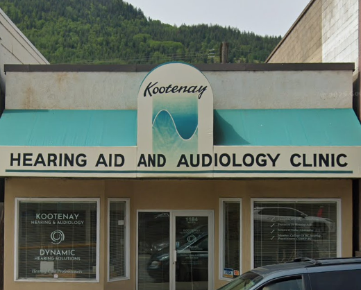 Kootenay Hearing Aid and Audiology Clinic storefront with teal awning and mountain backdrop.