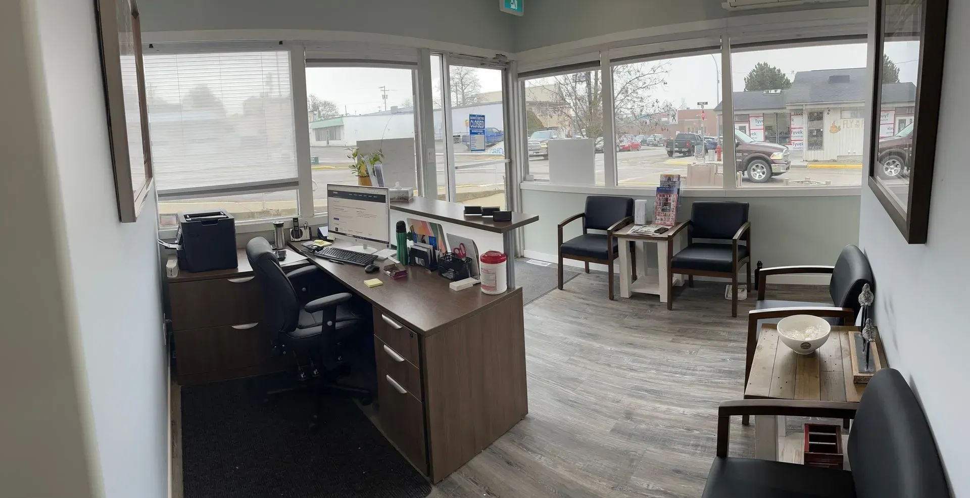 Office reception area with desk, chairs, and windows overlooking a street.
