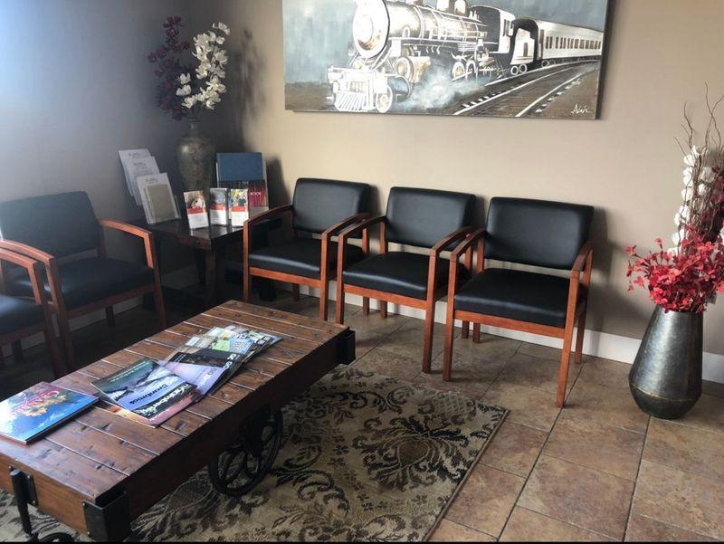 Waiting room with chairs, a coffee table, and a painting of a train.