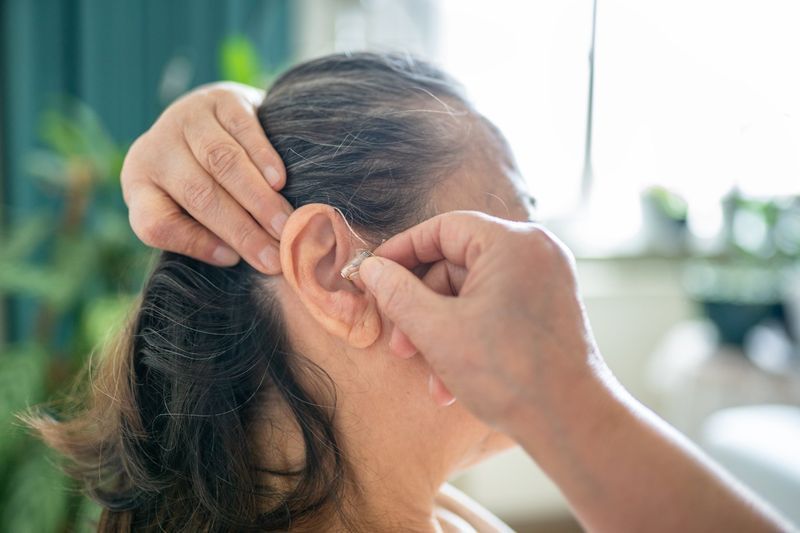 Person inserting a hearing aid into their ear.