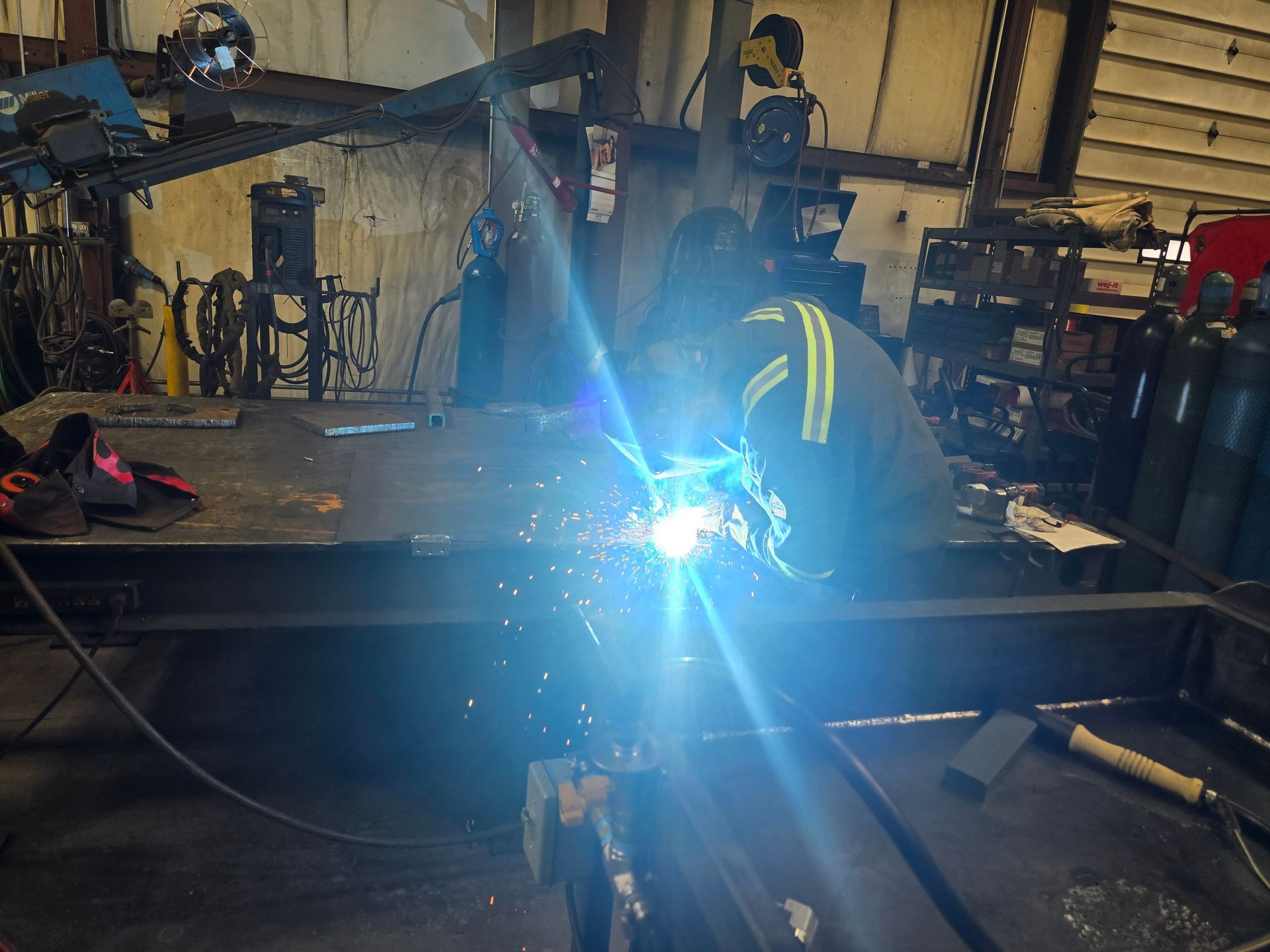Orange and gray industrial machine with hydraulic hoses and track treads.