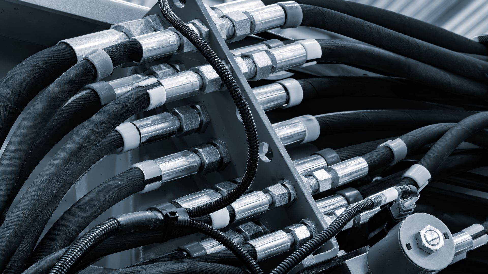 Hydraulic hoses and metal fittings connected to the industrial machinery manifold part