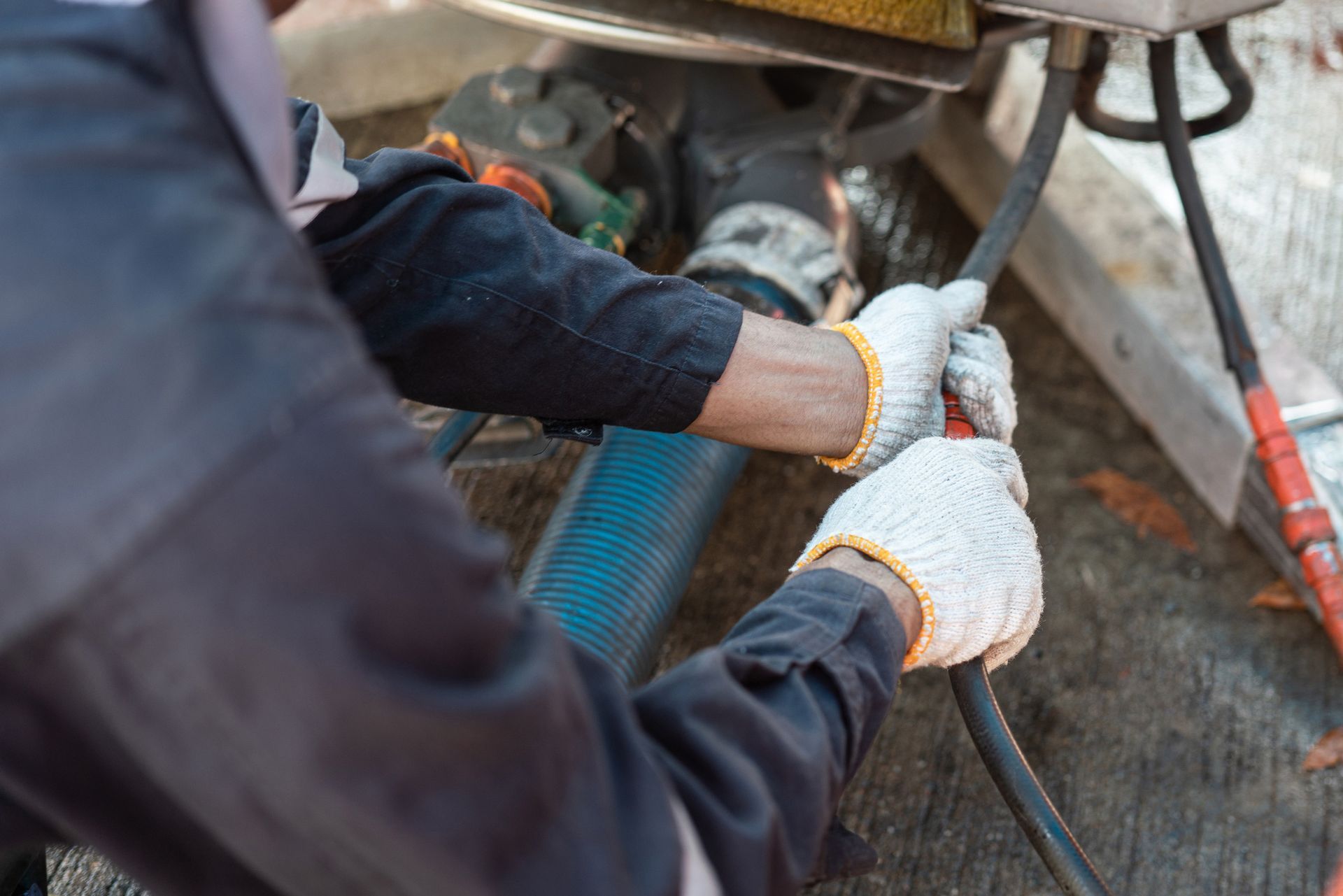 Person in work gloves connecting a hose outdoors.