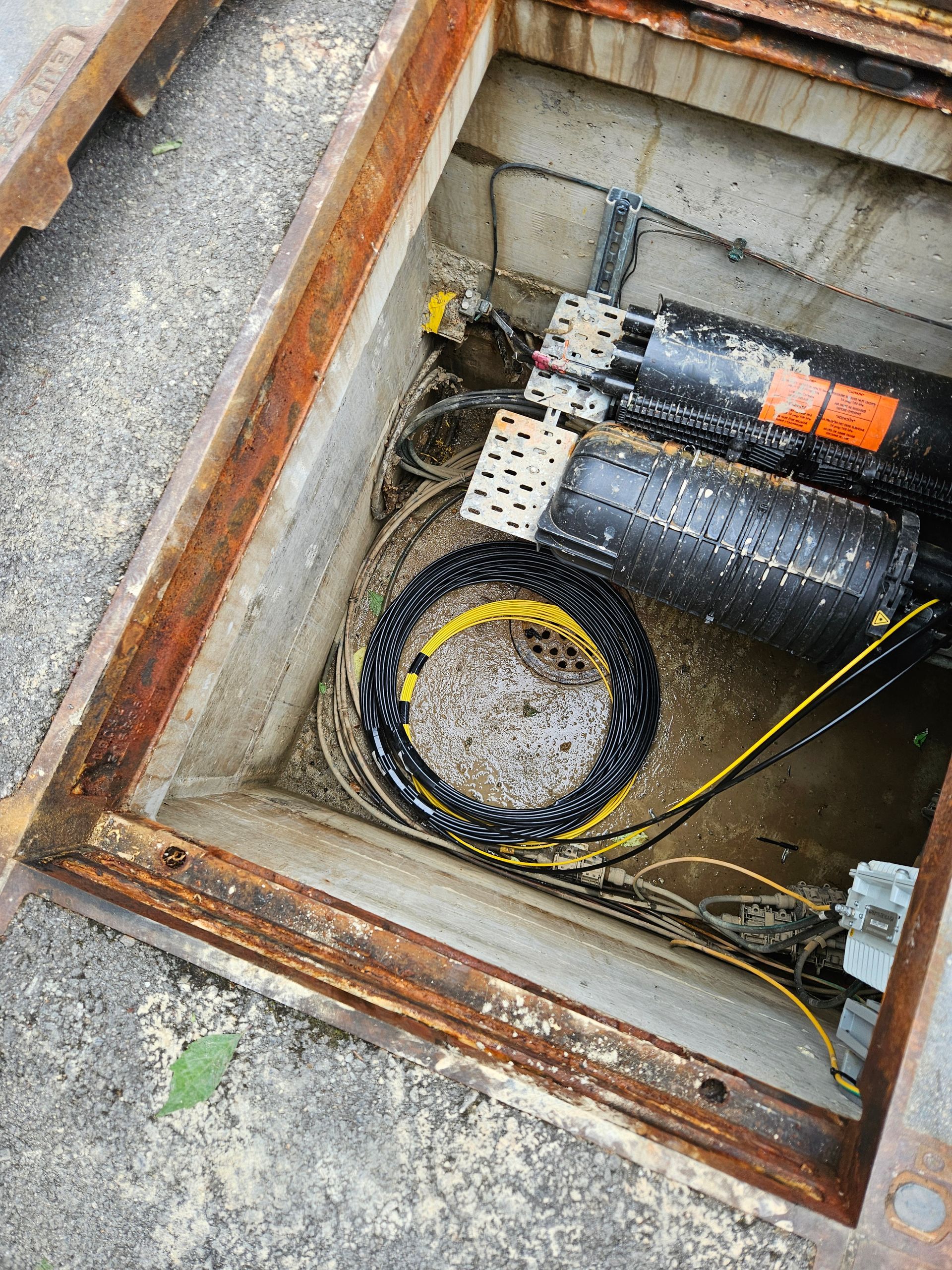 Une plaque d'égout remplie d'un tas de fils et de tuyaux