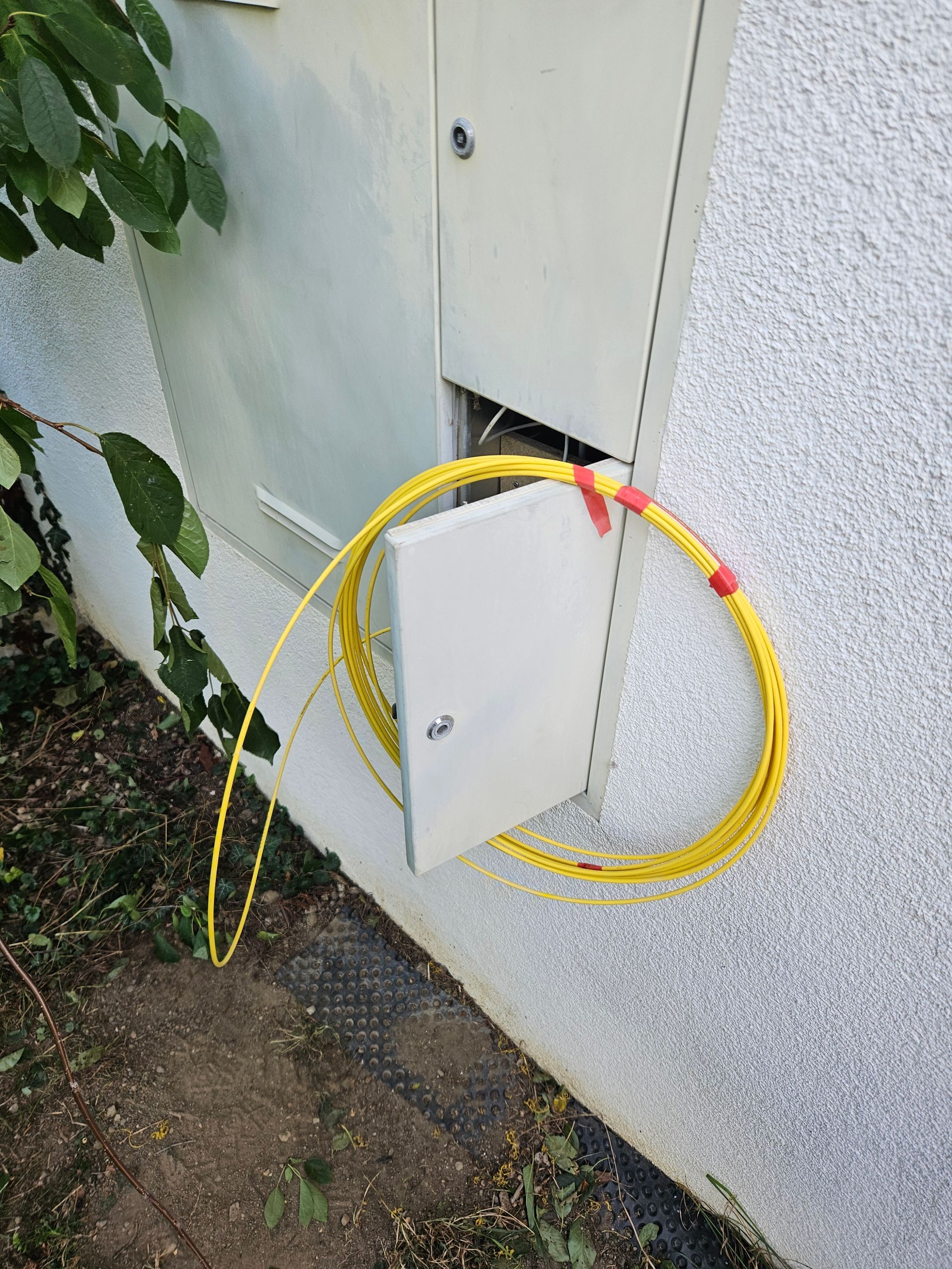 Un tuyau jaune est attaché à une boîte blanche sur le côté d'un bâtiment