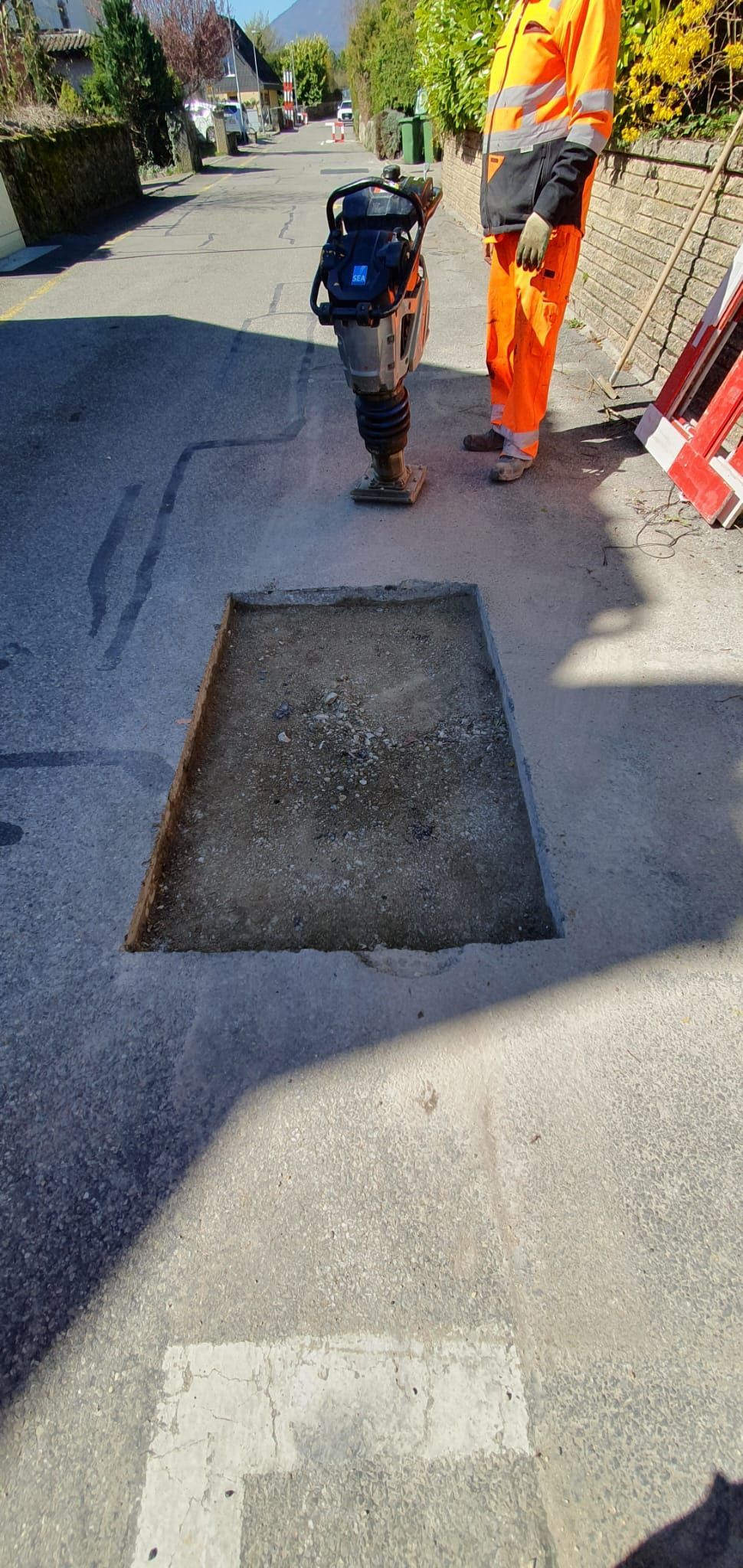 Un homme en pantalon orange se tient à côté d'un trou dans le sol