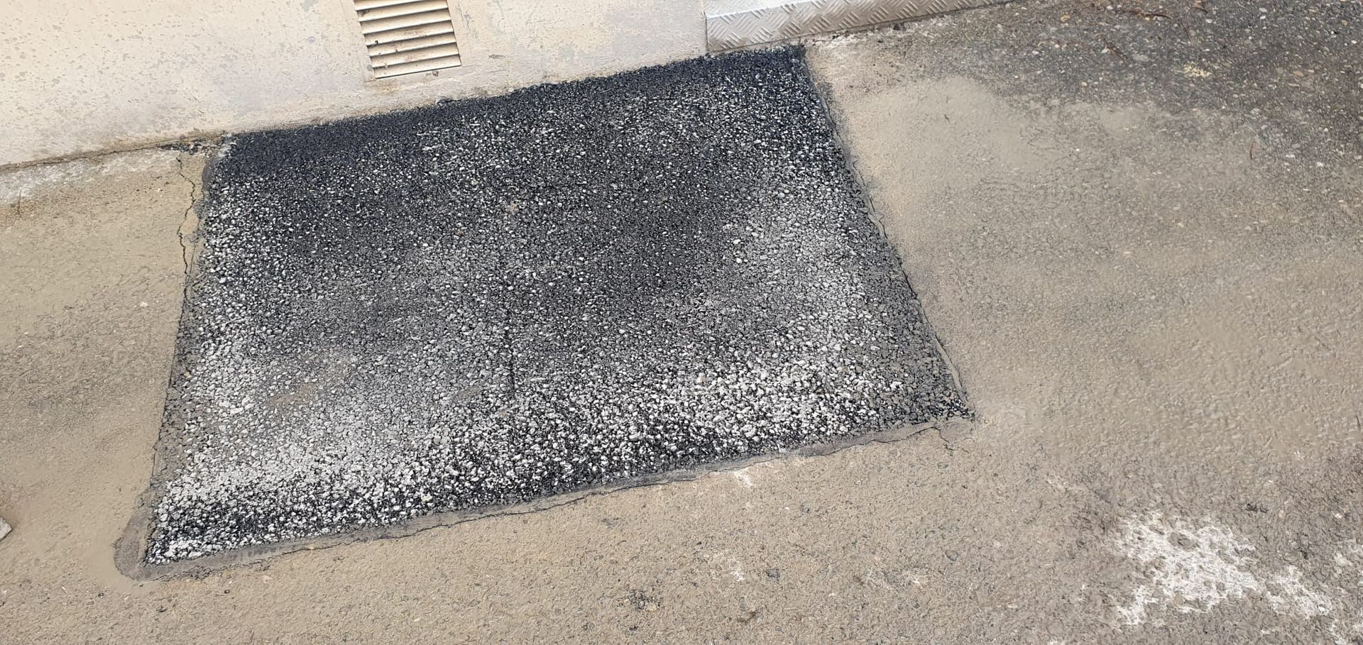 Un tapis noir est posé sur le sol à côté d'un drain.