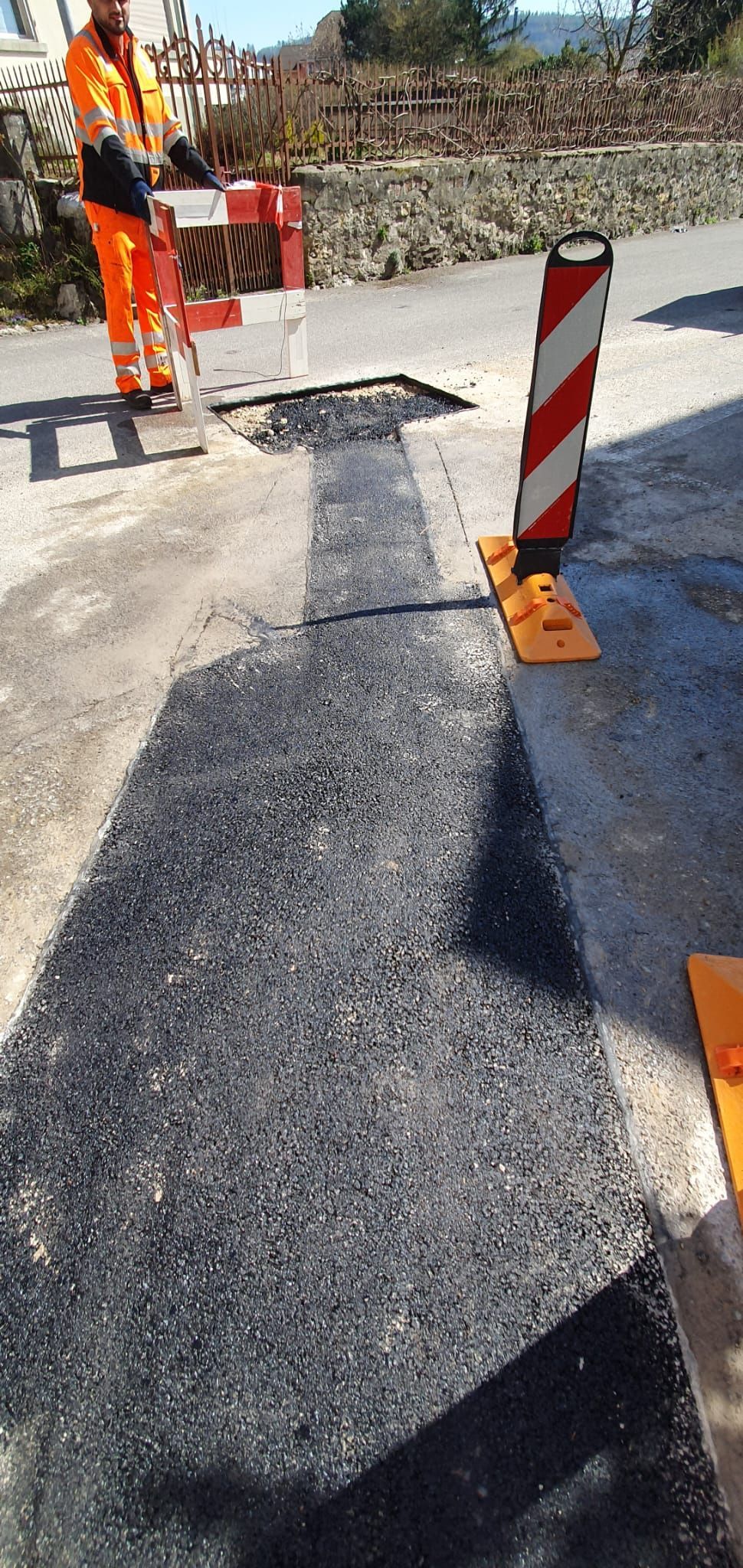 Un homme en pantalon orange travaille sur une route