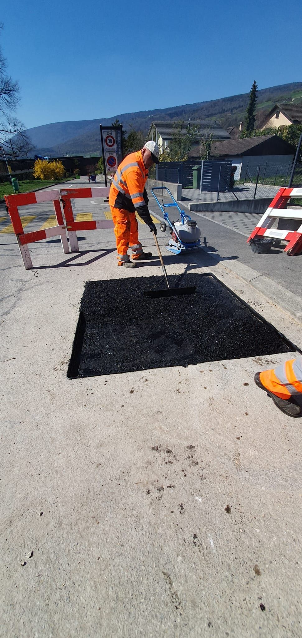 Un homme répand de l'asphalte noir sur le sol