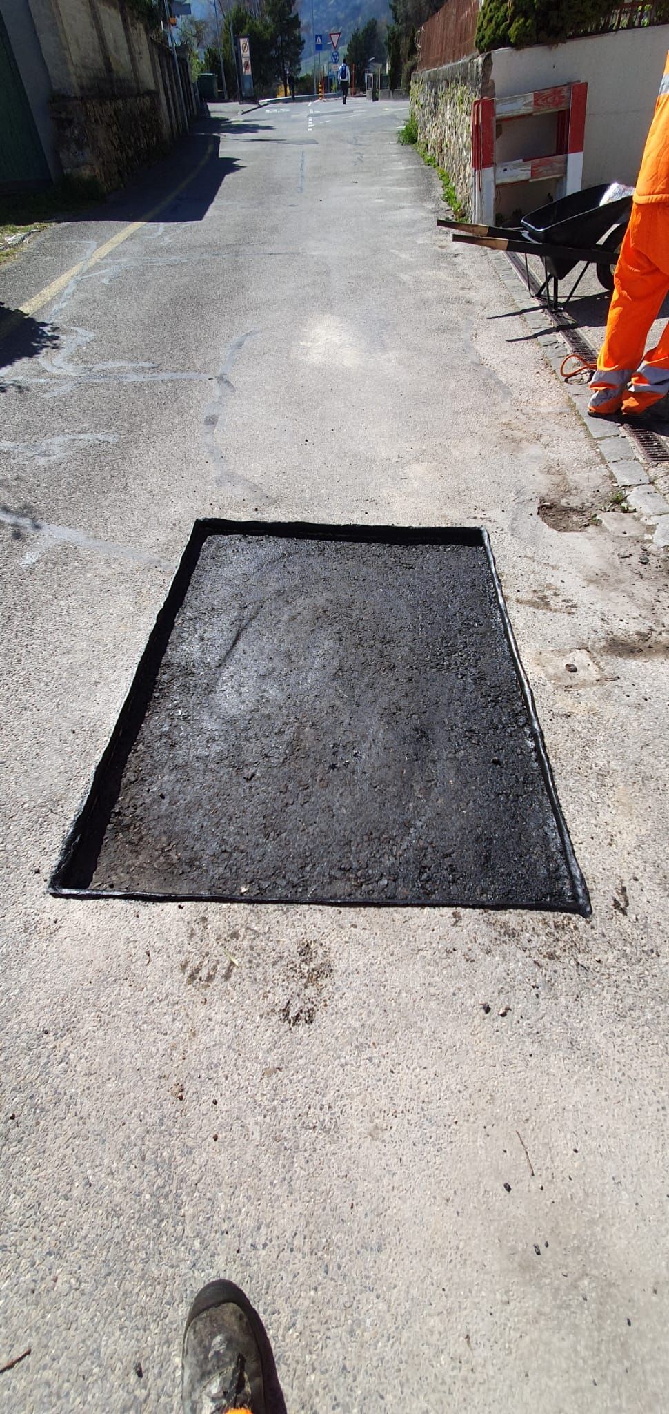Une personne se tient à côté d'une parcelle d'asphalte sur le bord d'une route.