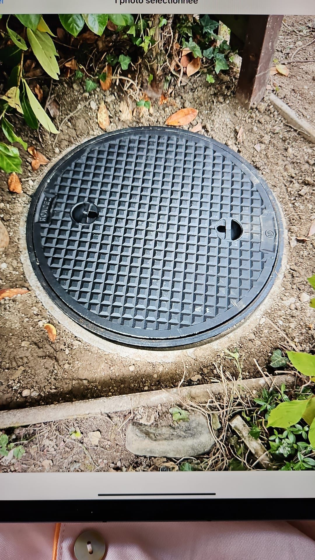 Un couvercle de trou avec un trou est posé sur le sol.