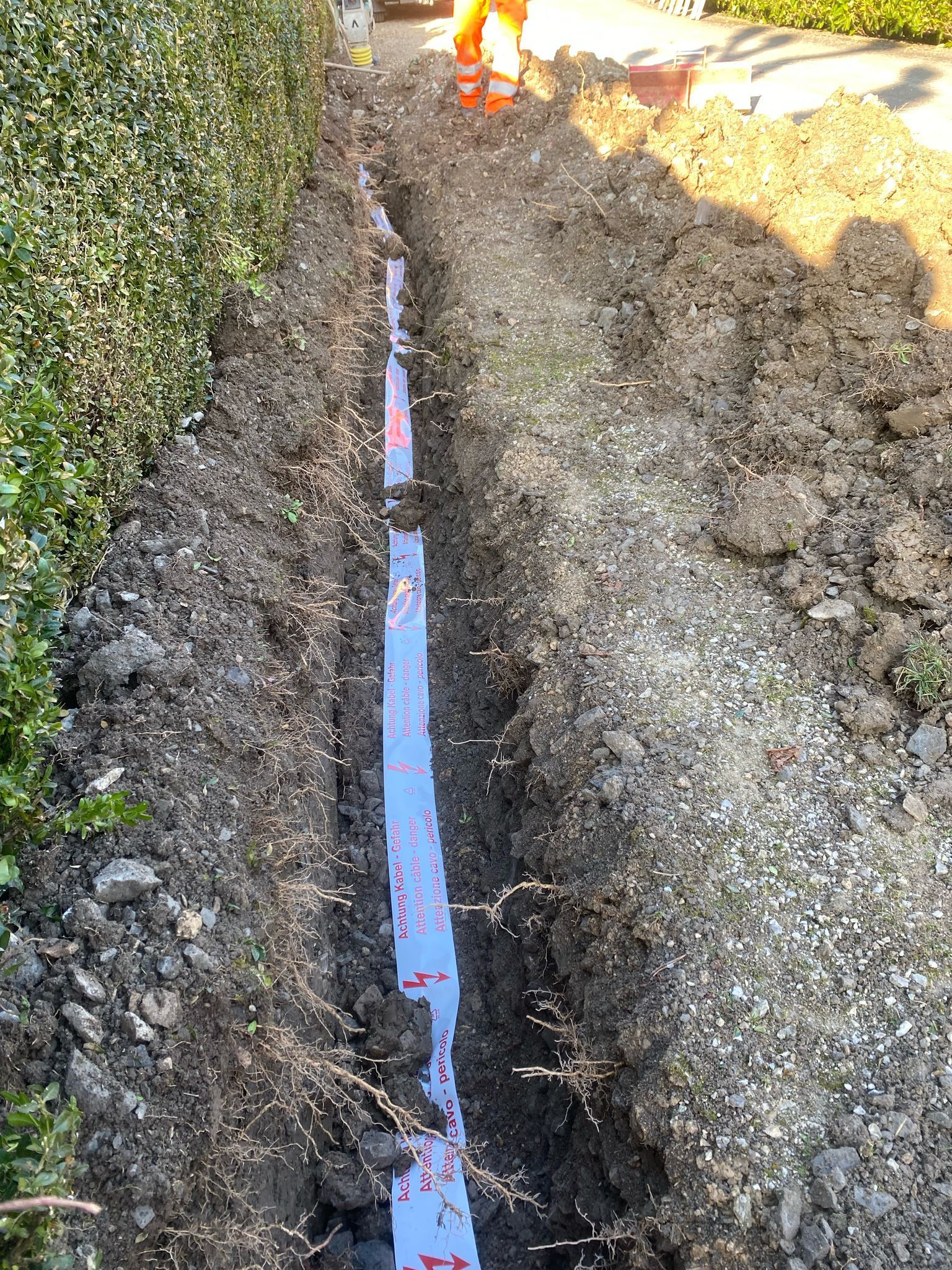 Un homme en salopette orange creuse un trou dans le sol