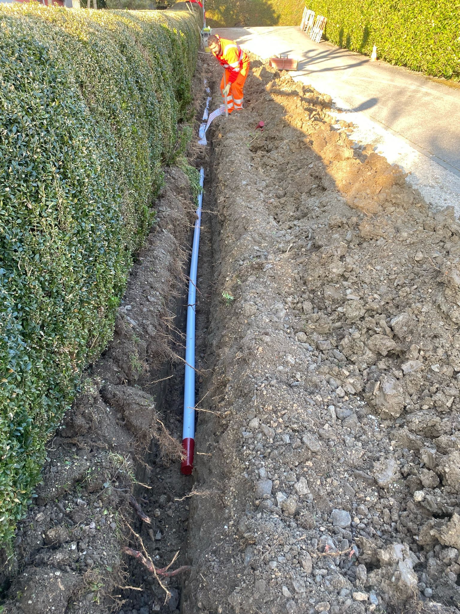 Un tuyau est en train d'être installé dans la terre à côté d'une route.