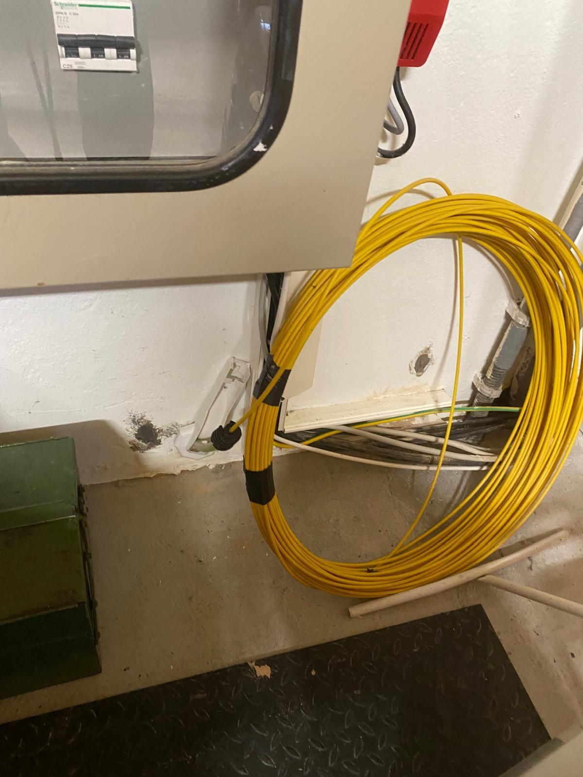 Un tuyau jaune est posé sur le sol à côté d'un mur