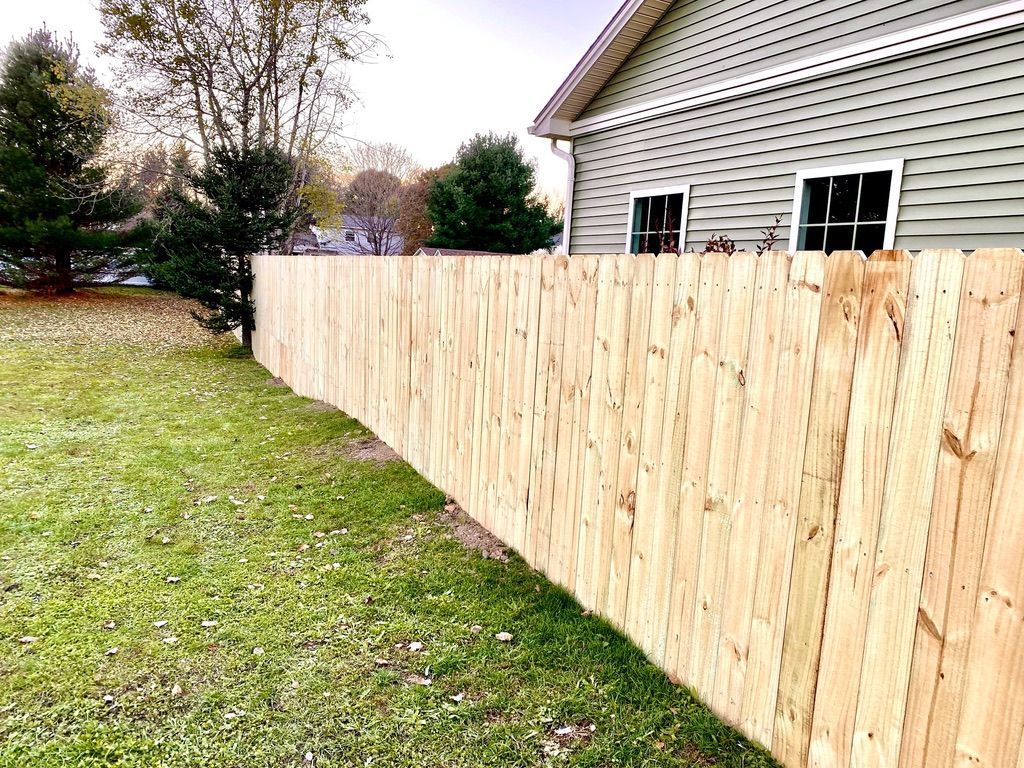A wooden fence is sitting in the grass in front of a house.