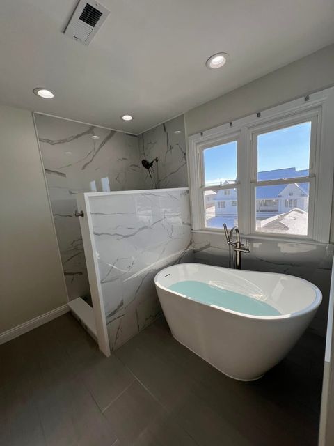 A bathroom with a tub , shower , and window.