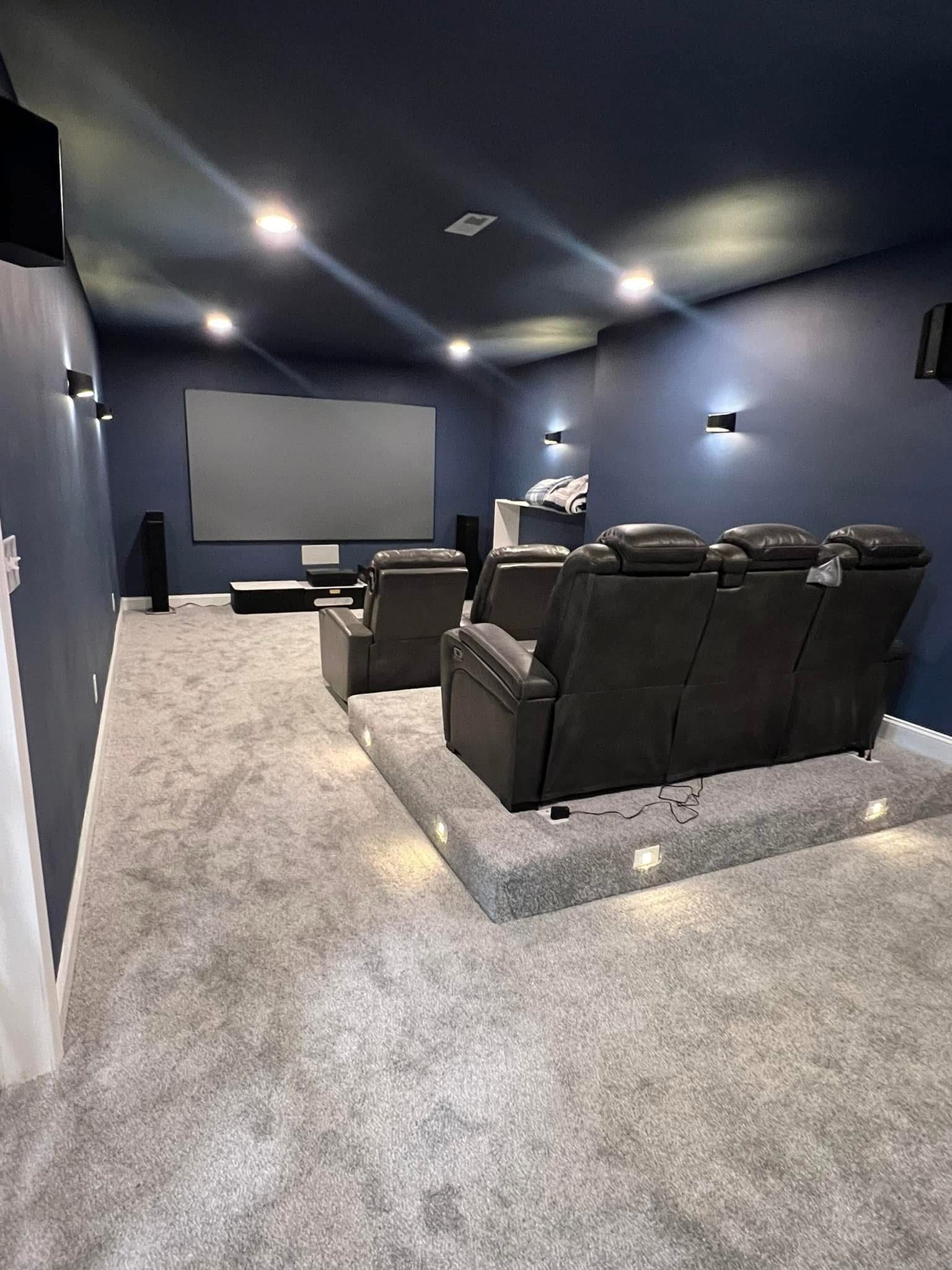 A home theater with a couch and chairs and a projector screen.