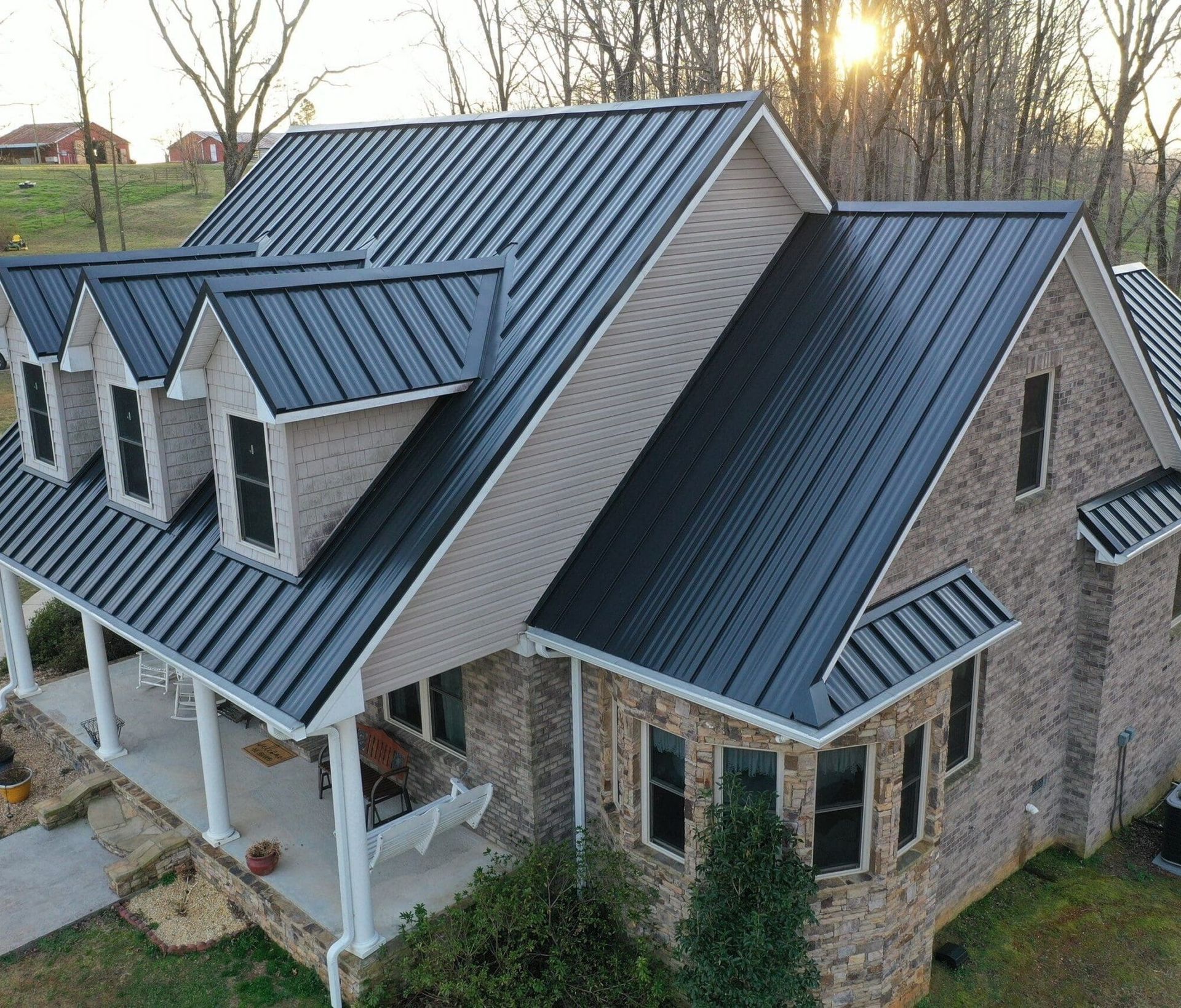 An aerial view of a house with a black roof and a porch.