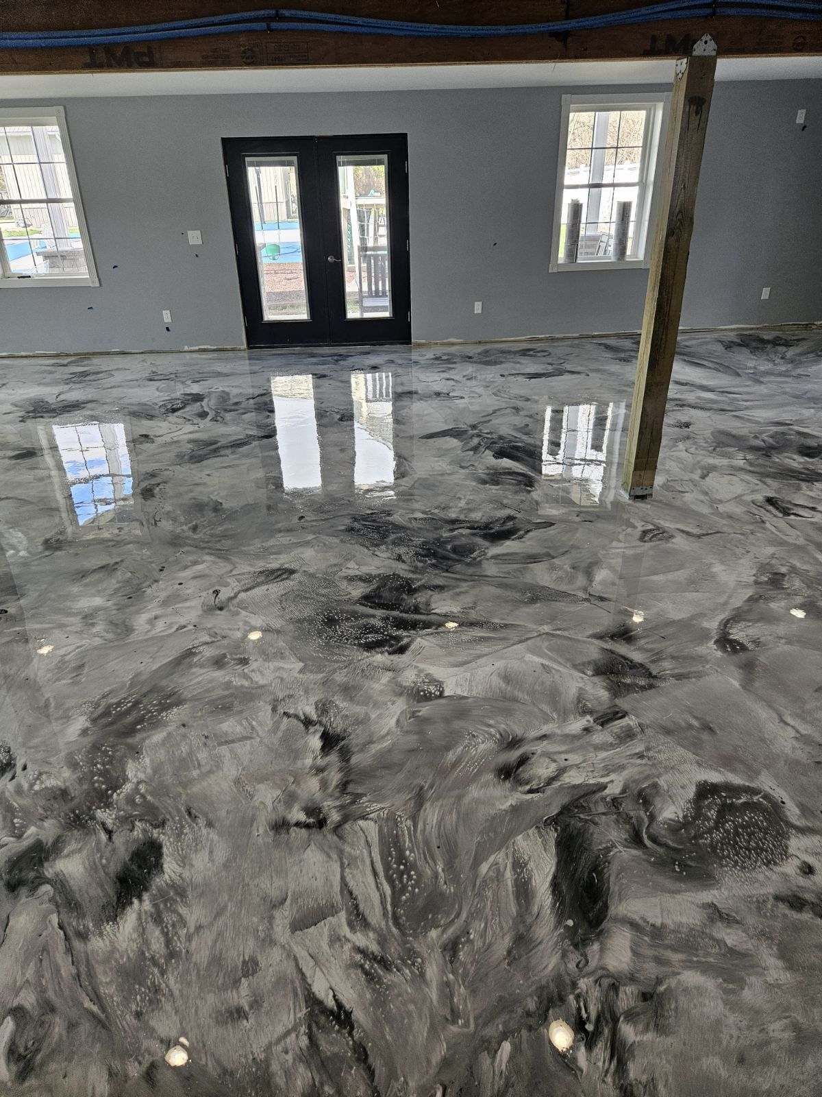 A room with a concrete floor and a reflection of a building in the floor.