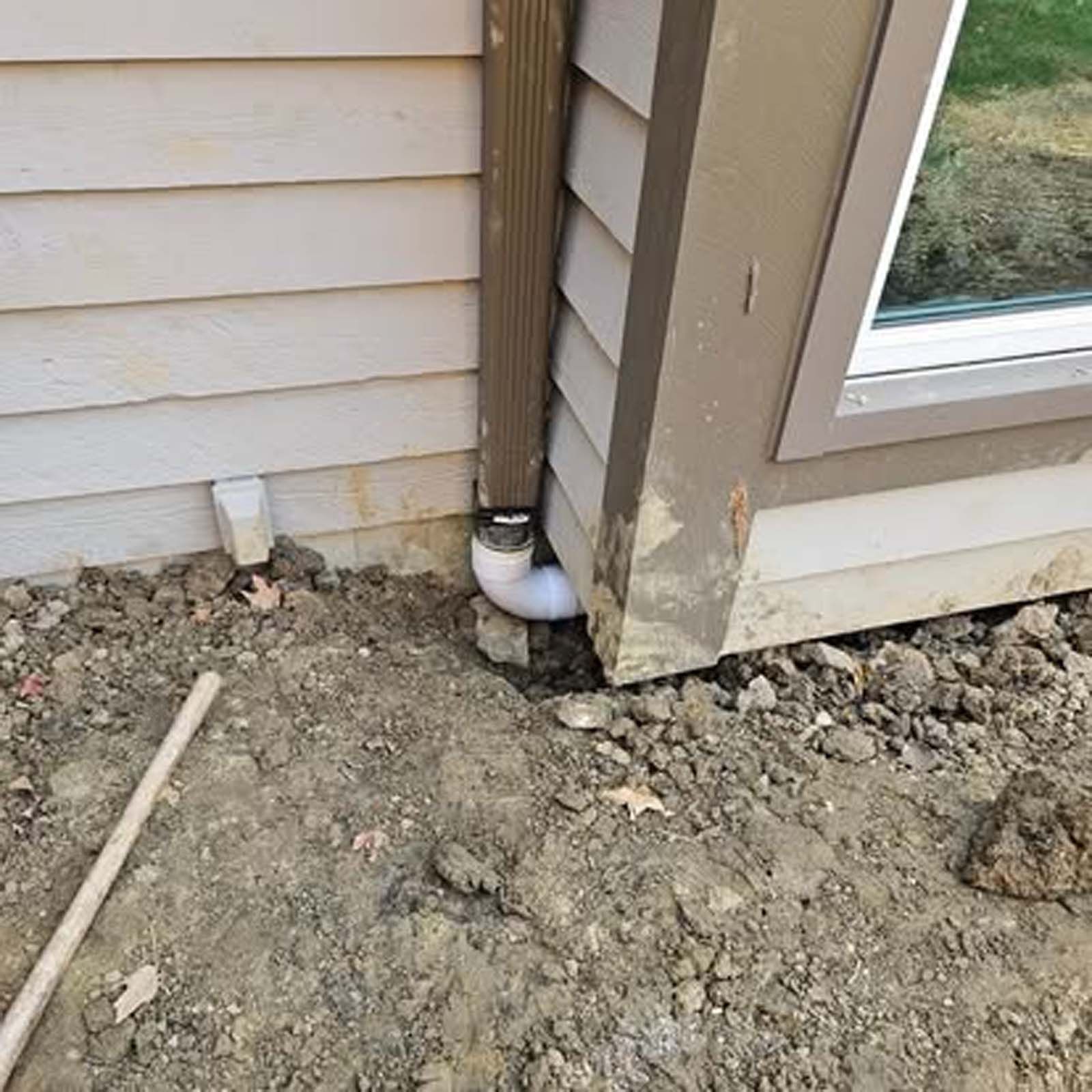 A drain pipe is being installed on the side of a house