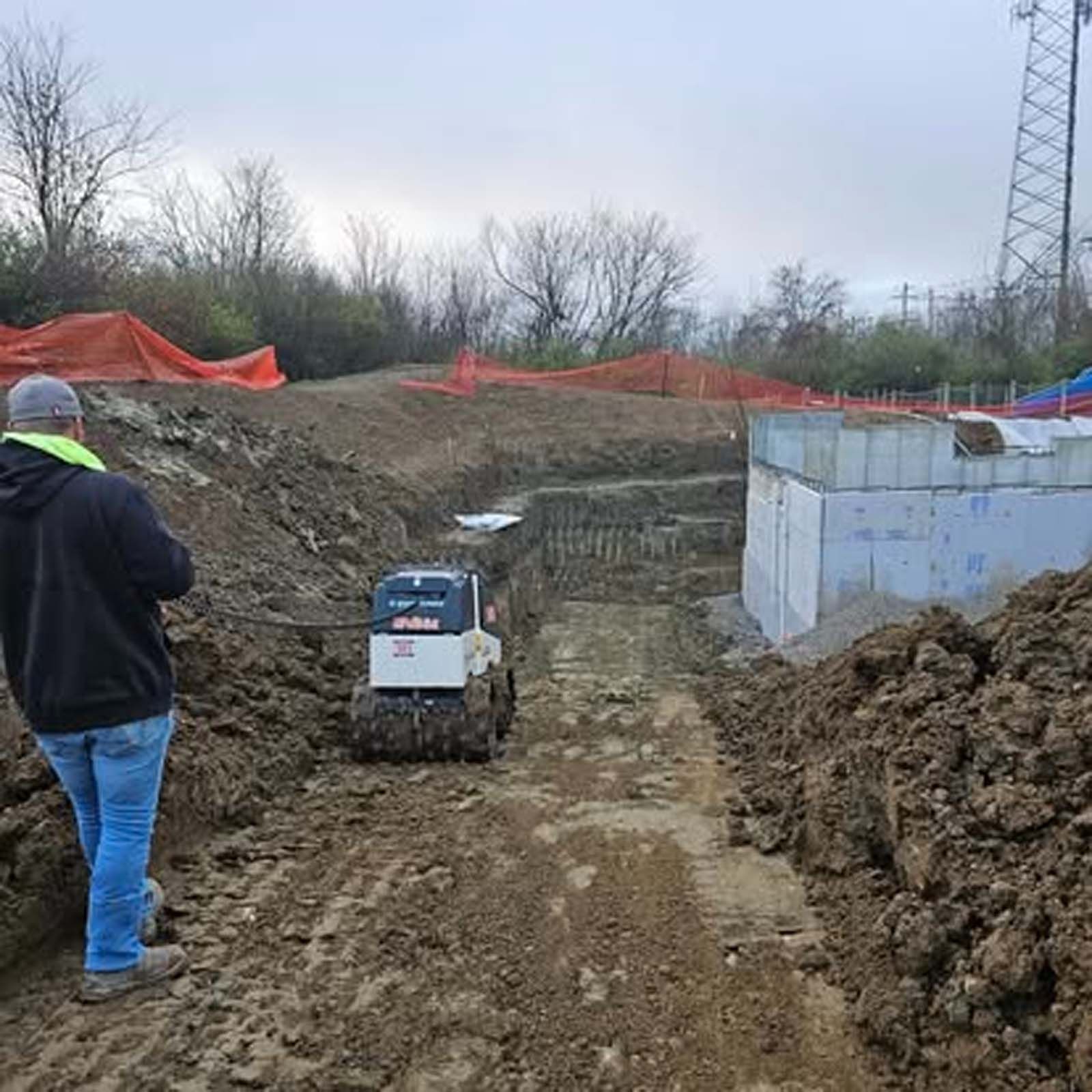 A man is standing next to a bulldozer on a dirt road.
