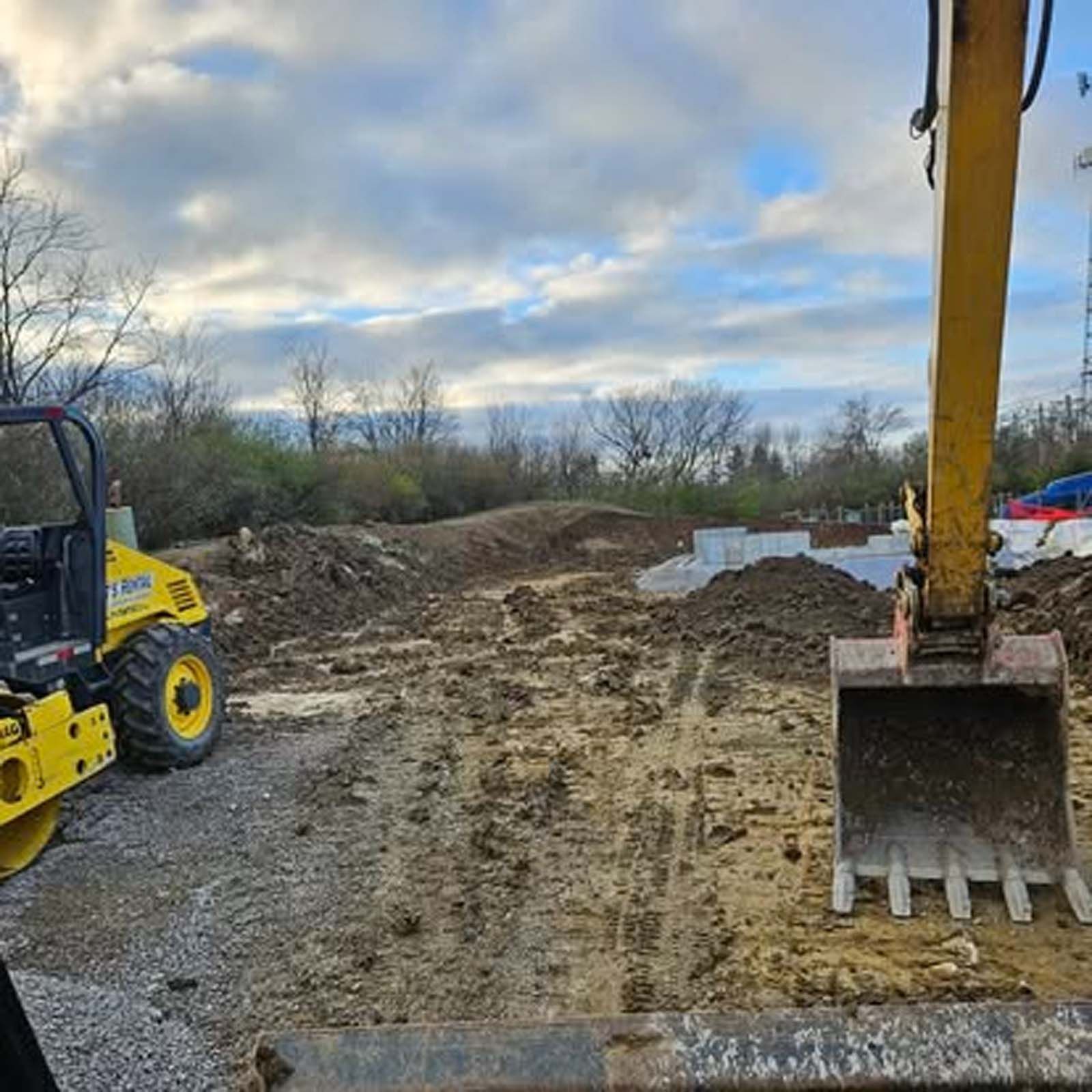A yellow excavator is digging a hole in a dirt field.