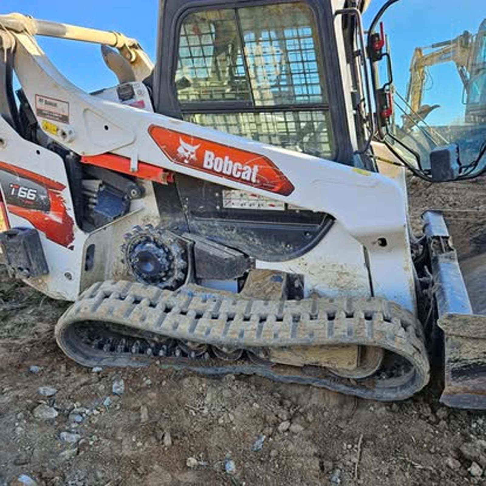A bobcat tractor is parked in the dirt on a construction site.